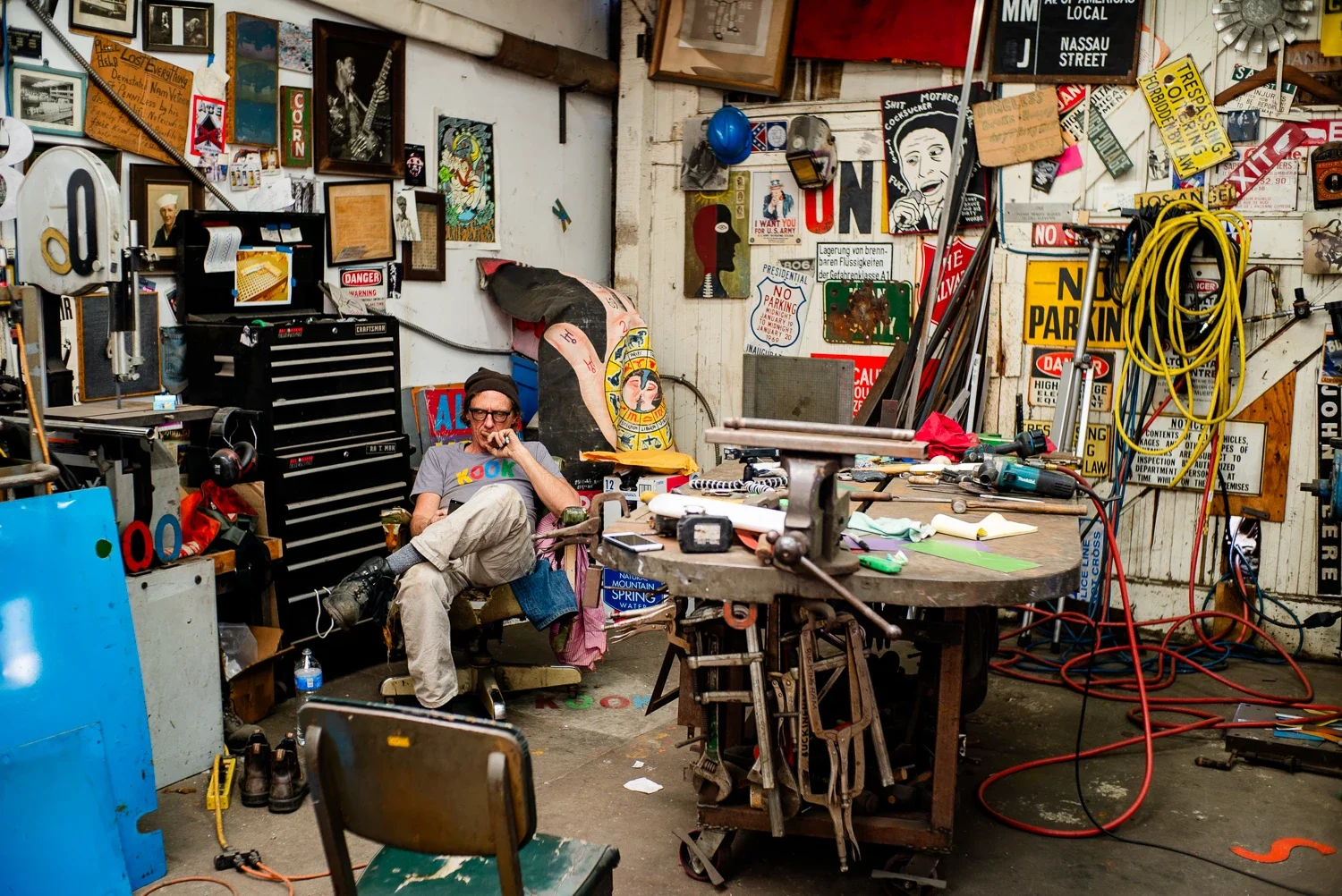 David Buckingham sits in the corner of his chaotic studio surrounded with artpieces and welding equipment