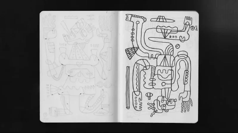 Open sketchbook with abstract, doodle-style drawings of various shapes and figures on white pages, set against a black background.