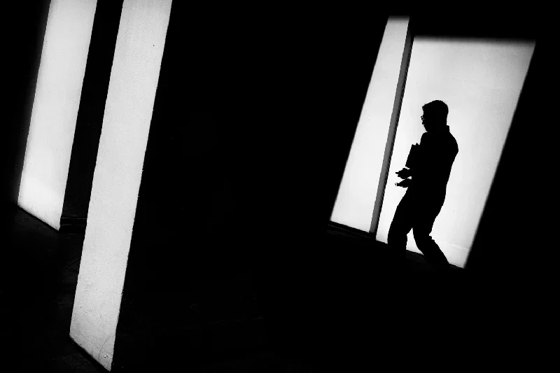 Silhouette of a person walking in an art gallery or museum with illuminated display panels.