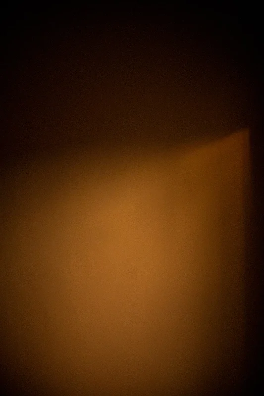 A dark room with a faint glow on the wall from a light source outside the frame.