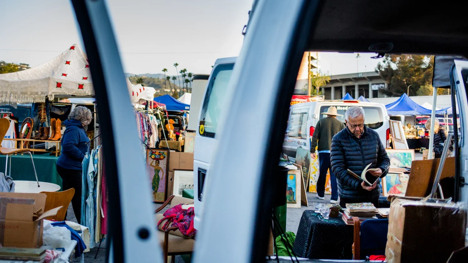 Jim Heimann perusing items in pasadena swap meet seen through an open van