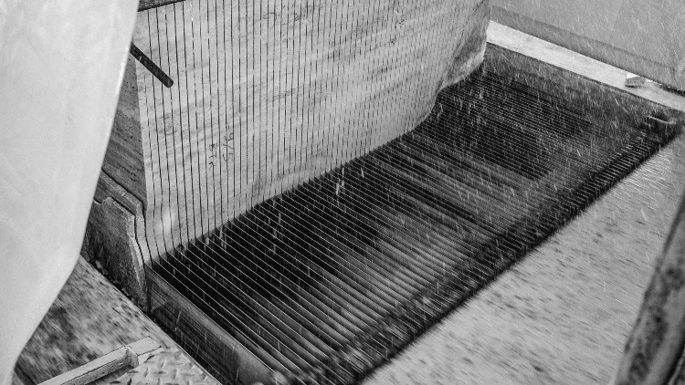 An industrial machine detail cutting a block of marble into thin layers, covered with water spray and drips