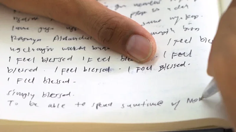 Close-up of a hand writing on a piece of paper with a pen.