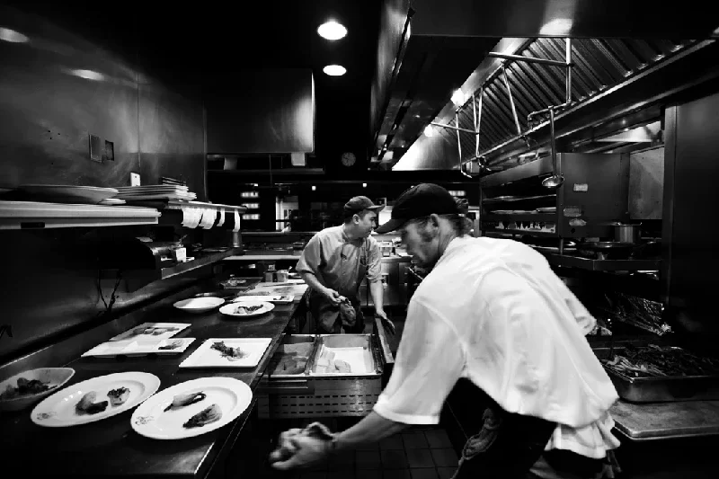 Two chefs working in a professional kitchen, preparing dishes and plating food.