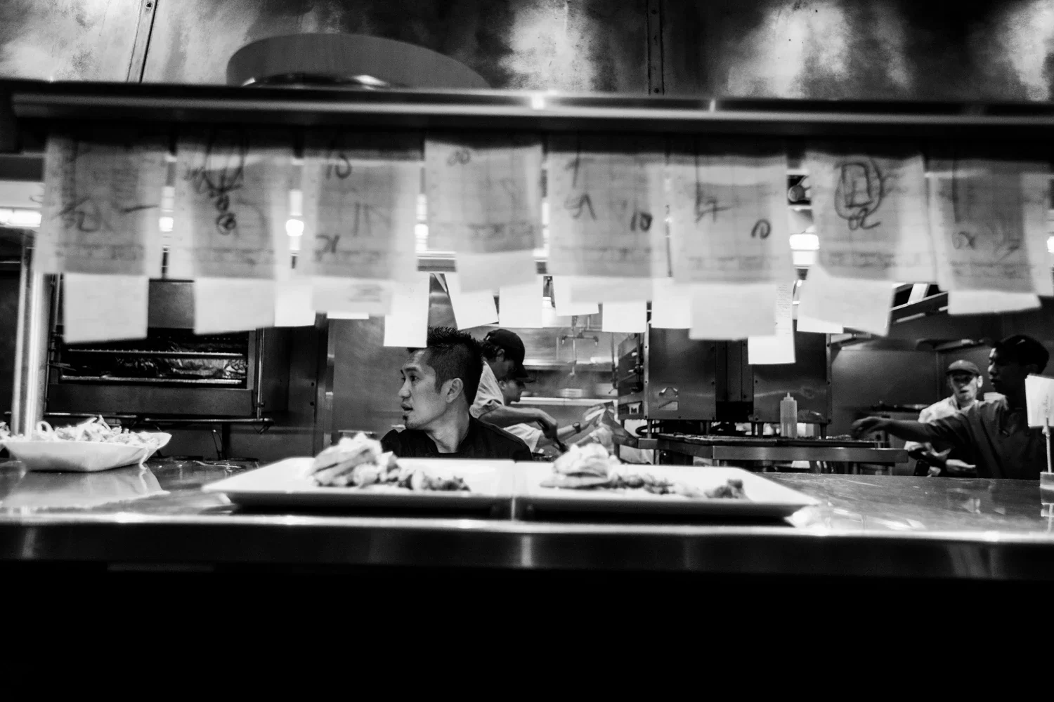 Chef Edgar Agbayani in front of the counter showing mounting food orders