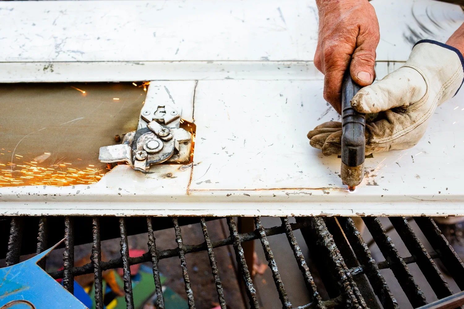 cutting metal with a torch as sparks run through an opening