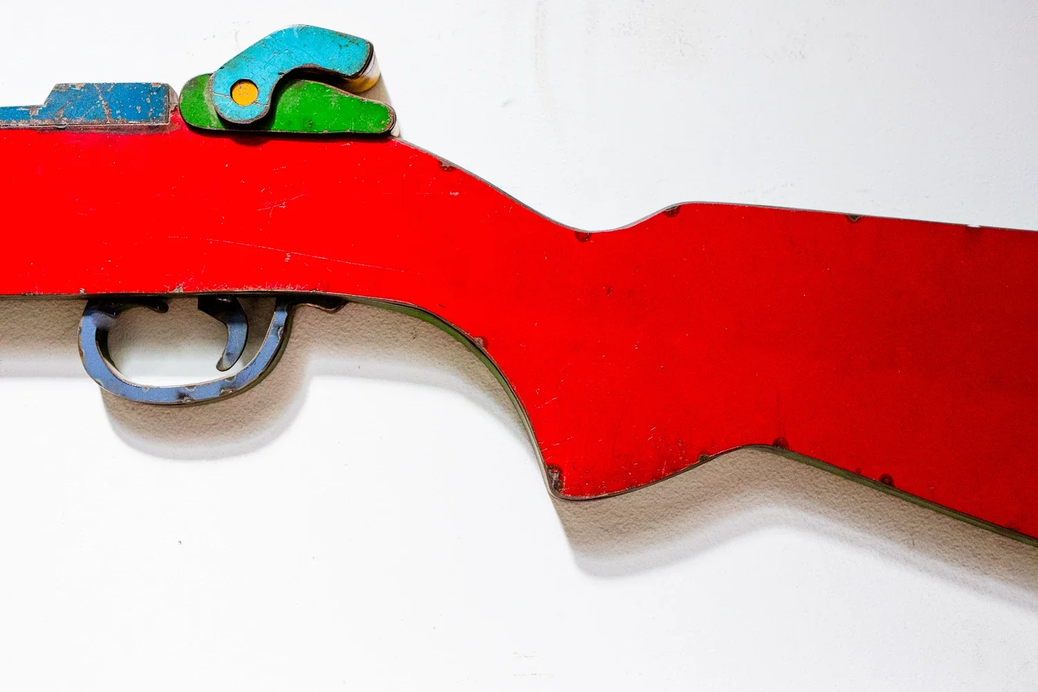 detail shot of an art piece in the shape of a rifle in colorful old metal