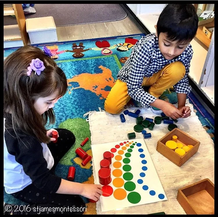Two students working cooperatively with the Sensorial Area's Knobless Cylinders Extension Lesson.
