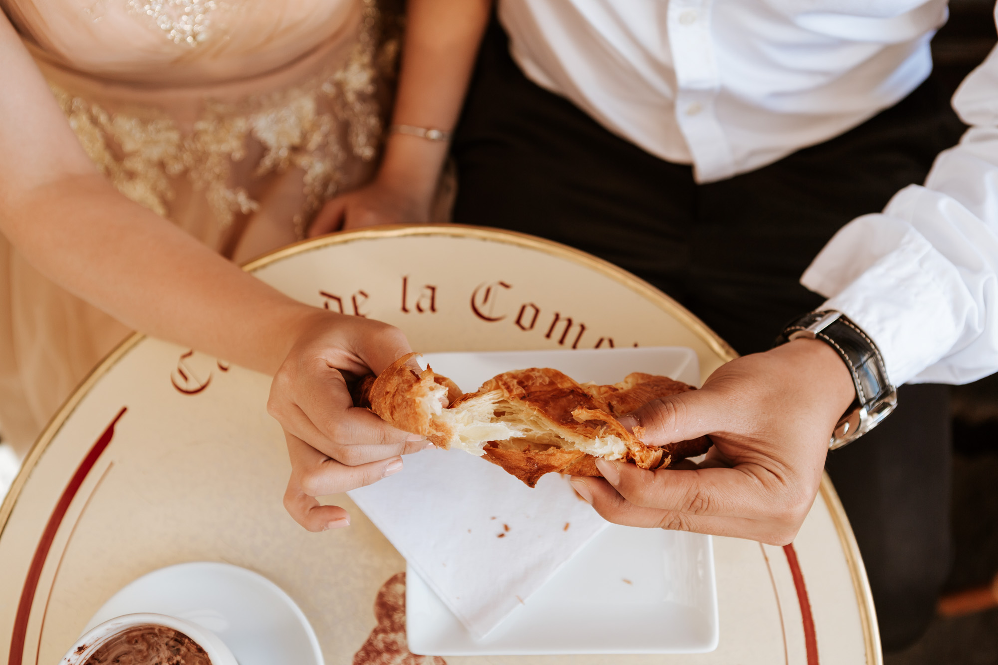Cafe de la comedie couple pre-wedding photo session sharing croissant captured by Photographer in Paris Federico Guendel