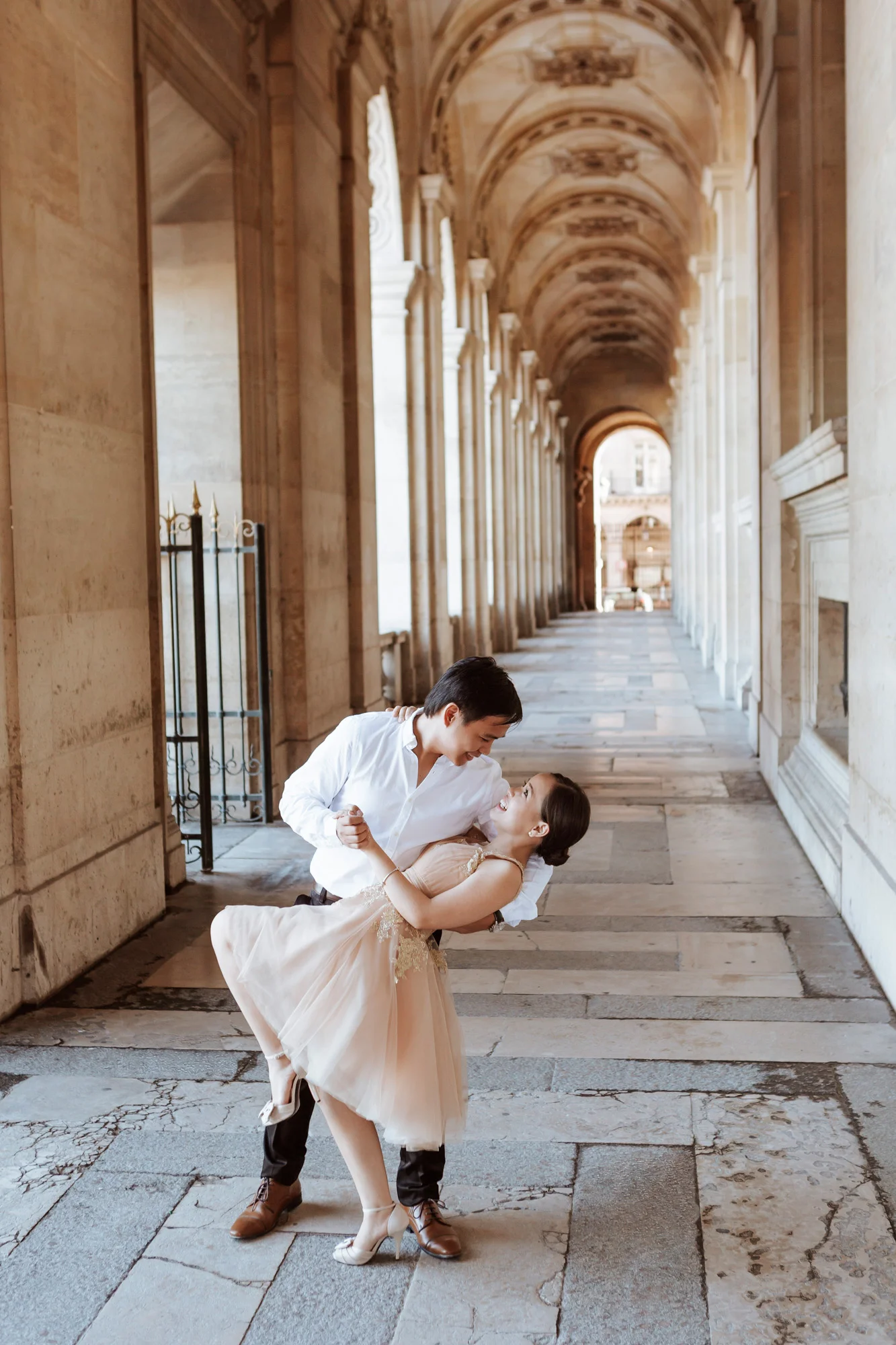 Pre-wedding couple portrait dancing in a corridor in the Louvre Museum captured by Paris Photographer Federico Guendel