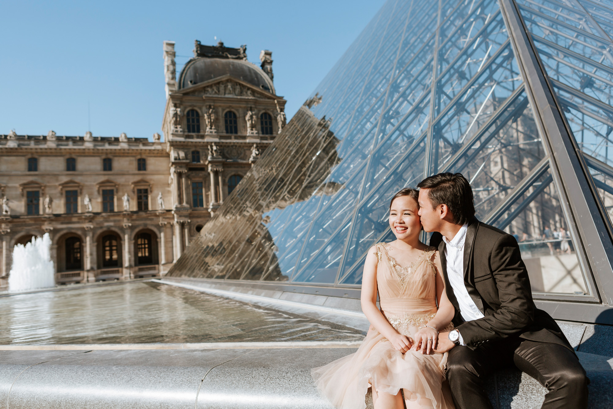 Pre-wedding couple portrait kissing at the courtyard of the Louvre Museum by the Pyramid captured by Paris Photographer Federico Guendel