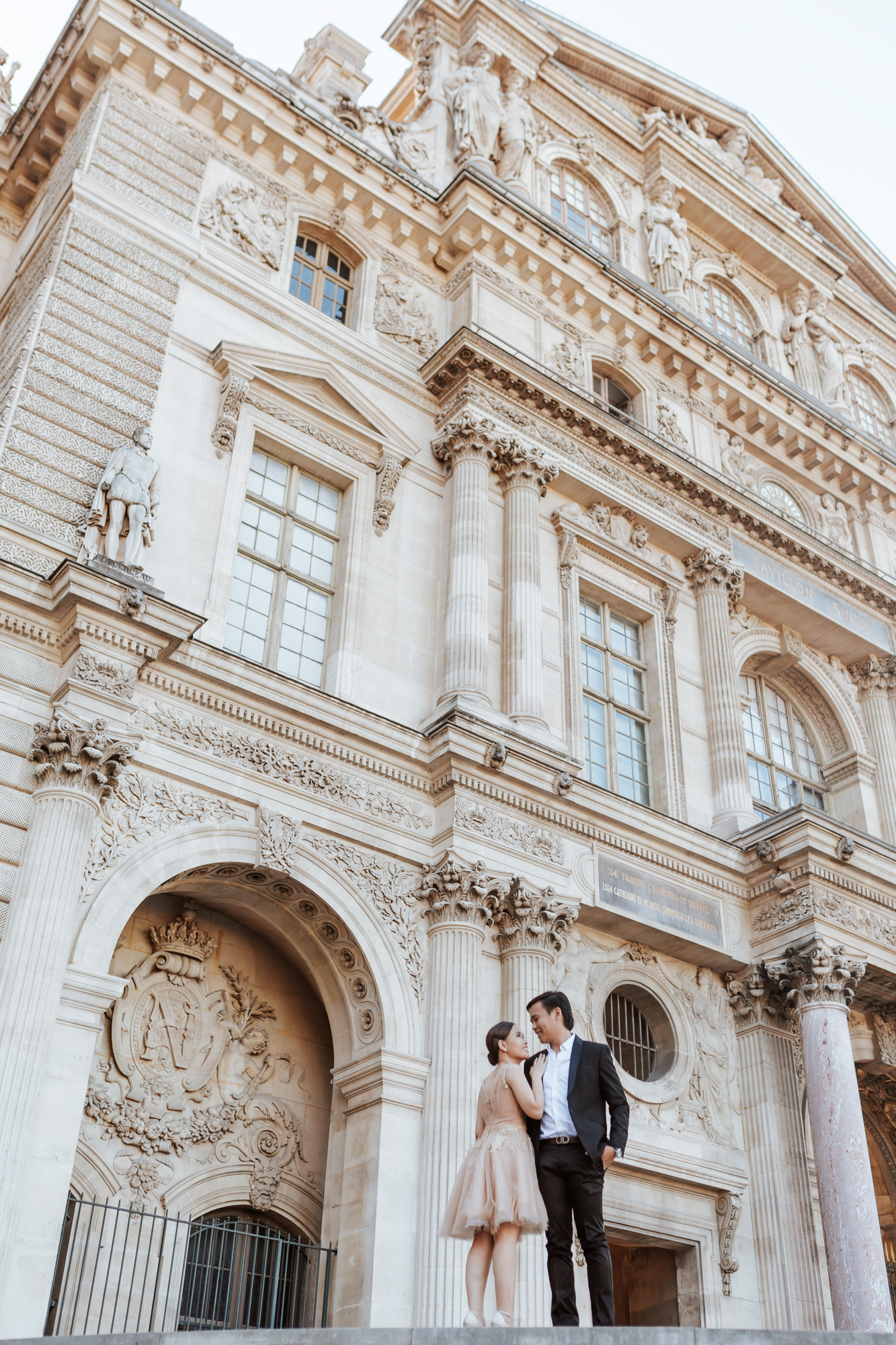 Pre-wedding couple portrait standing in the courtyard of the Louvre Museum captured by Paris Photographer Federico Guendel