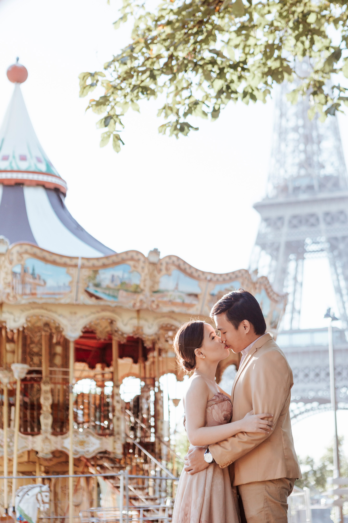 Pre-wedding couple portrait session kissing by the carousel at the Eiffel Tower in sunrise captured by Photographer in Paris Federico Guendel