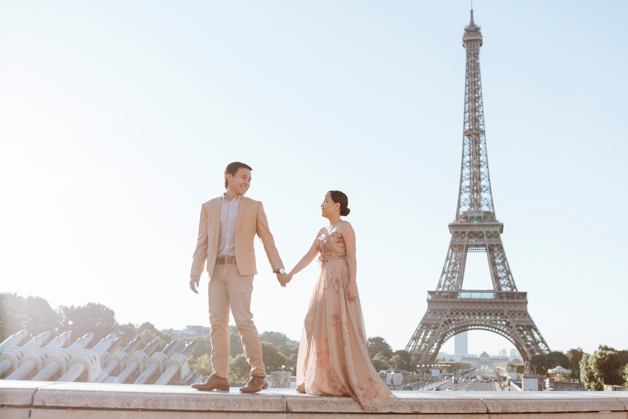 Pre-wedding couple portrait session holding hands walking by the Eiffel Tower at Trocadero in sunrise captured by Photographer in Paris Federico Guendel