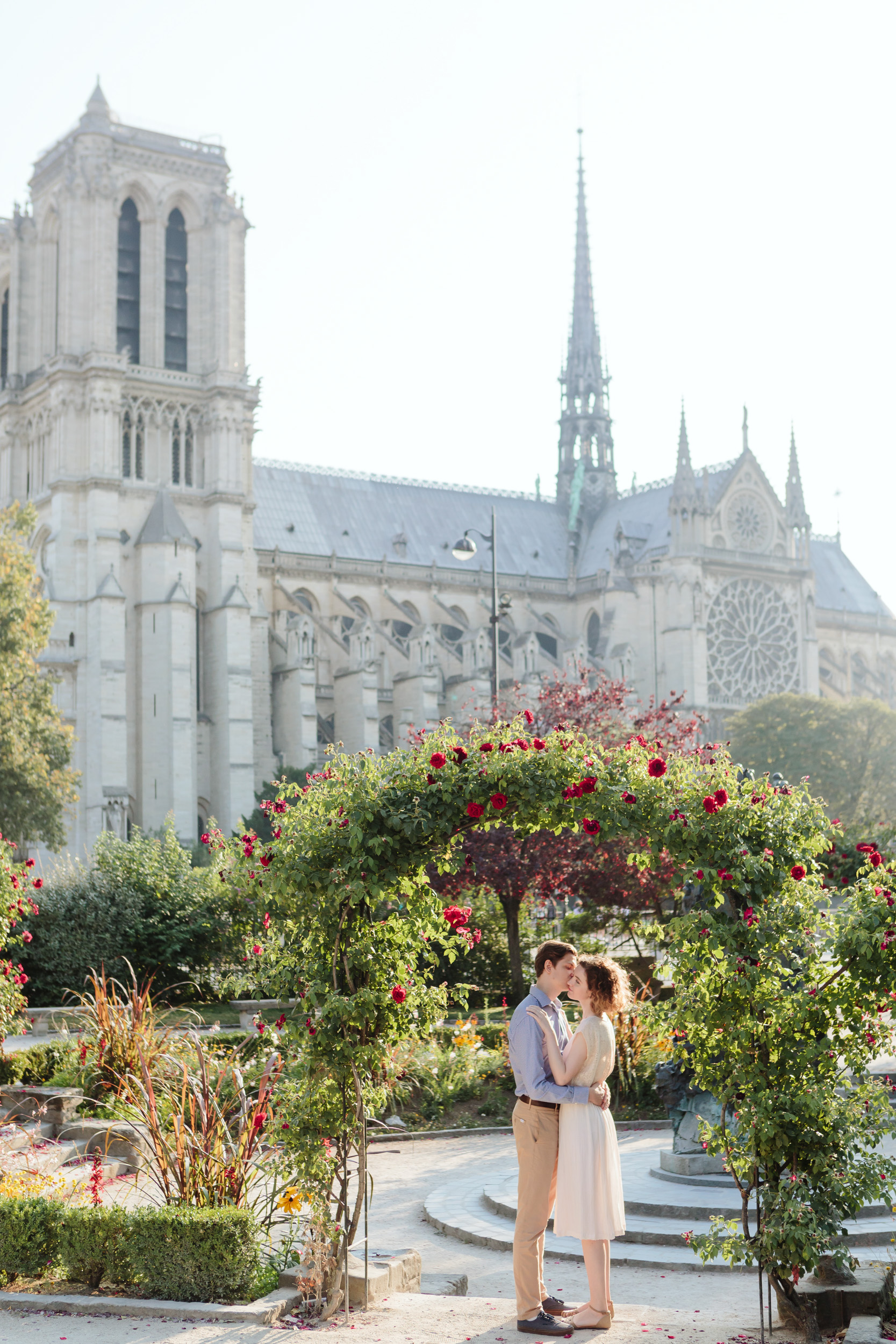 Couple in love kissing by Notre Dame Cathedral rose garden in Paris captured by Paris Photographer Federico Guendel IheartParisFr