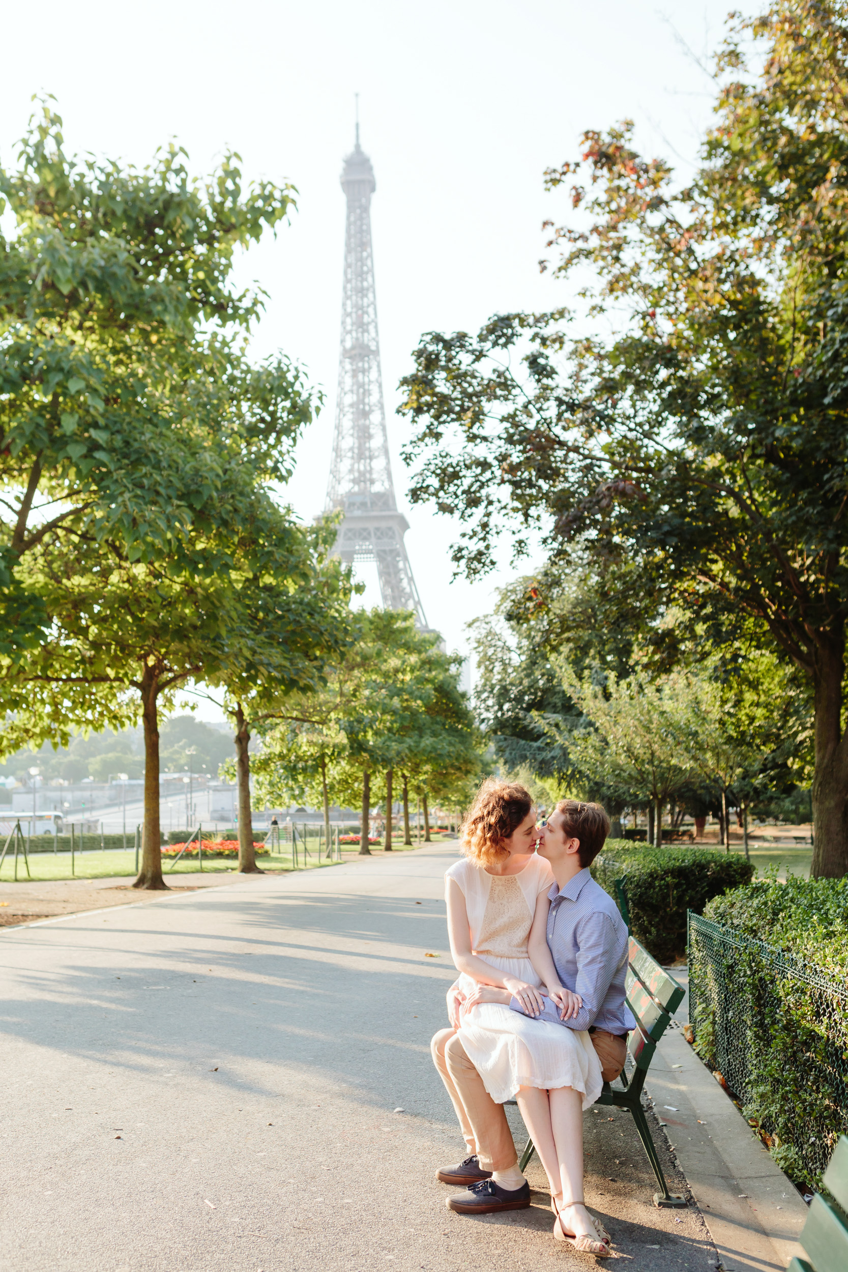 Couple sitting on a bench and kissing at Trocadero by the Eiffel Tower at sunrise captured by Paris Photographer Federico Guendel IheartParisFr