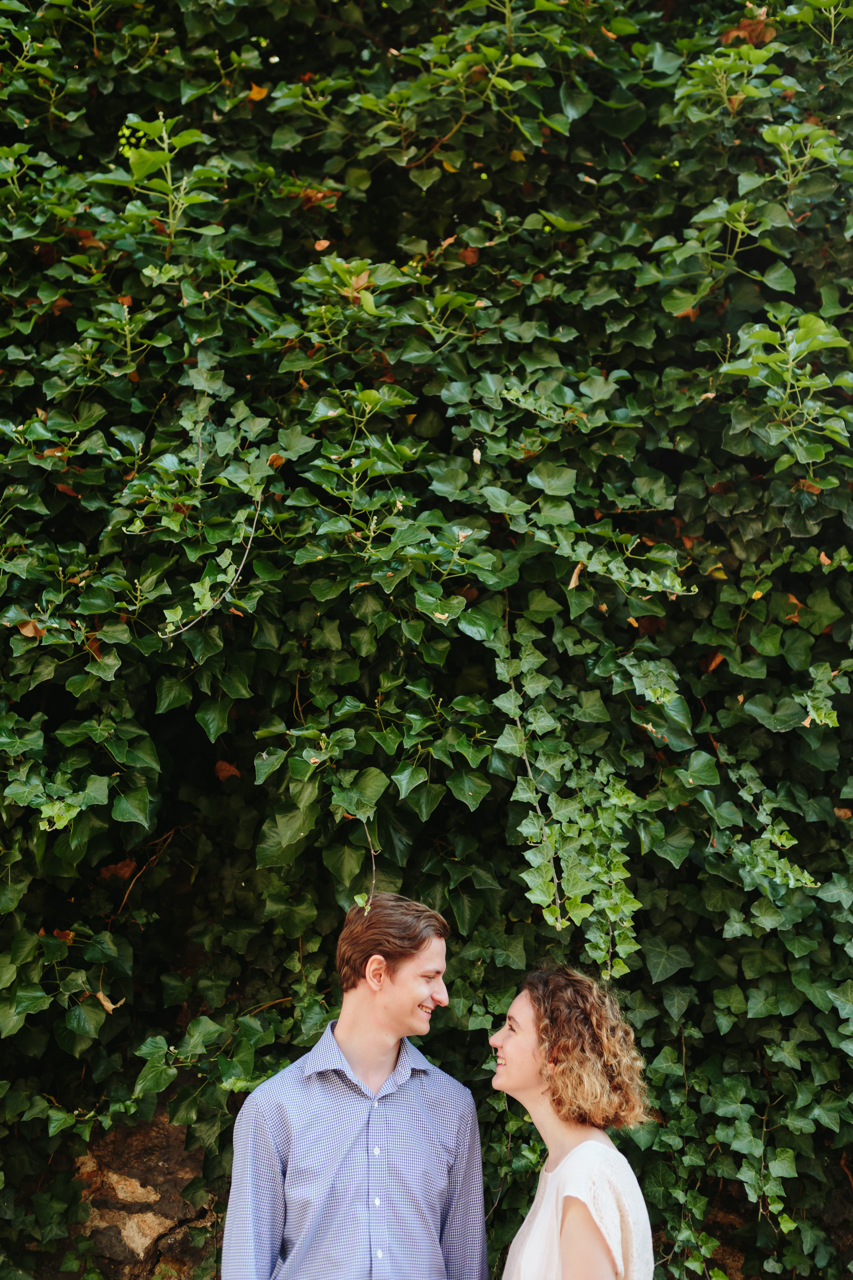Couple in love smiling standing by wild ivy wall at Montmartre captured by Paris Photographer Federico Guendel IheartParisFr