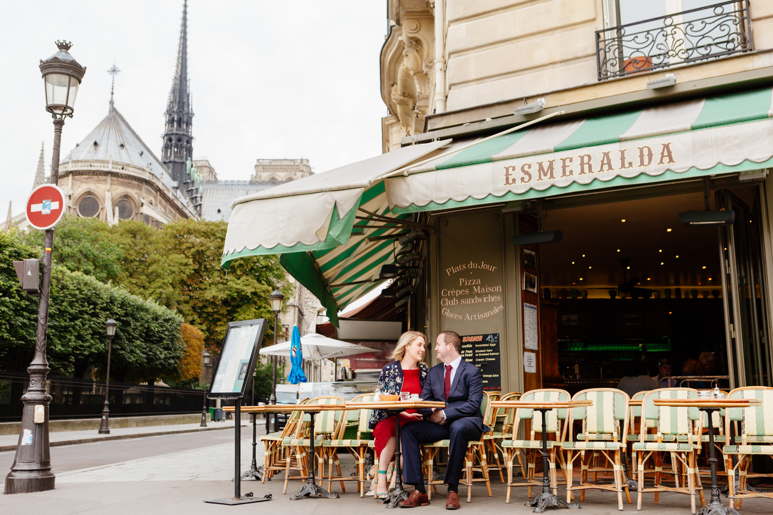 Couple sharing a croissant and coffee at cafe Esmeralda with the view of Notre Dame Cathedral captured by Paris Photographer Federico Guendel www.iheartparis.fr