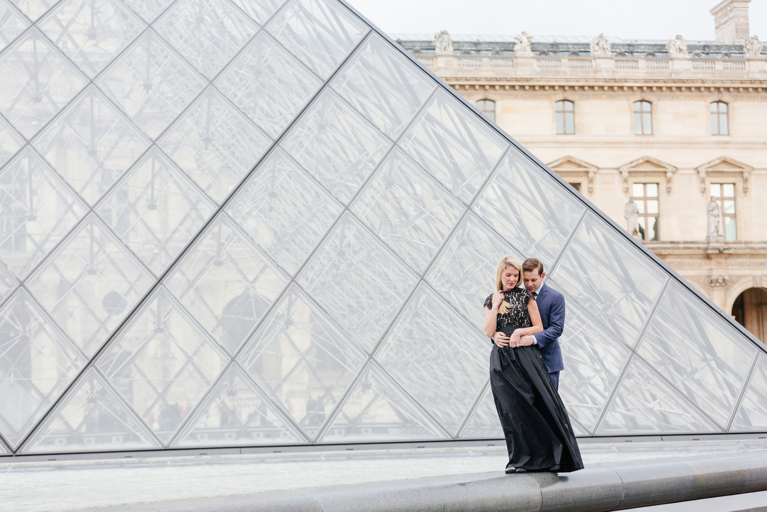 Paris vacation couple portrait standing in the courtyard of Louvre Museum by the Pyramid captured by Paris Photographer Federico Guendel www.iheartparis.fr