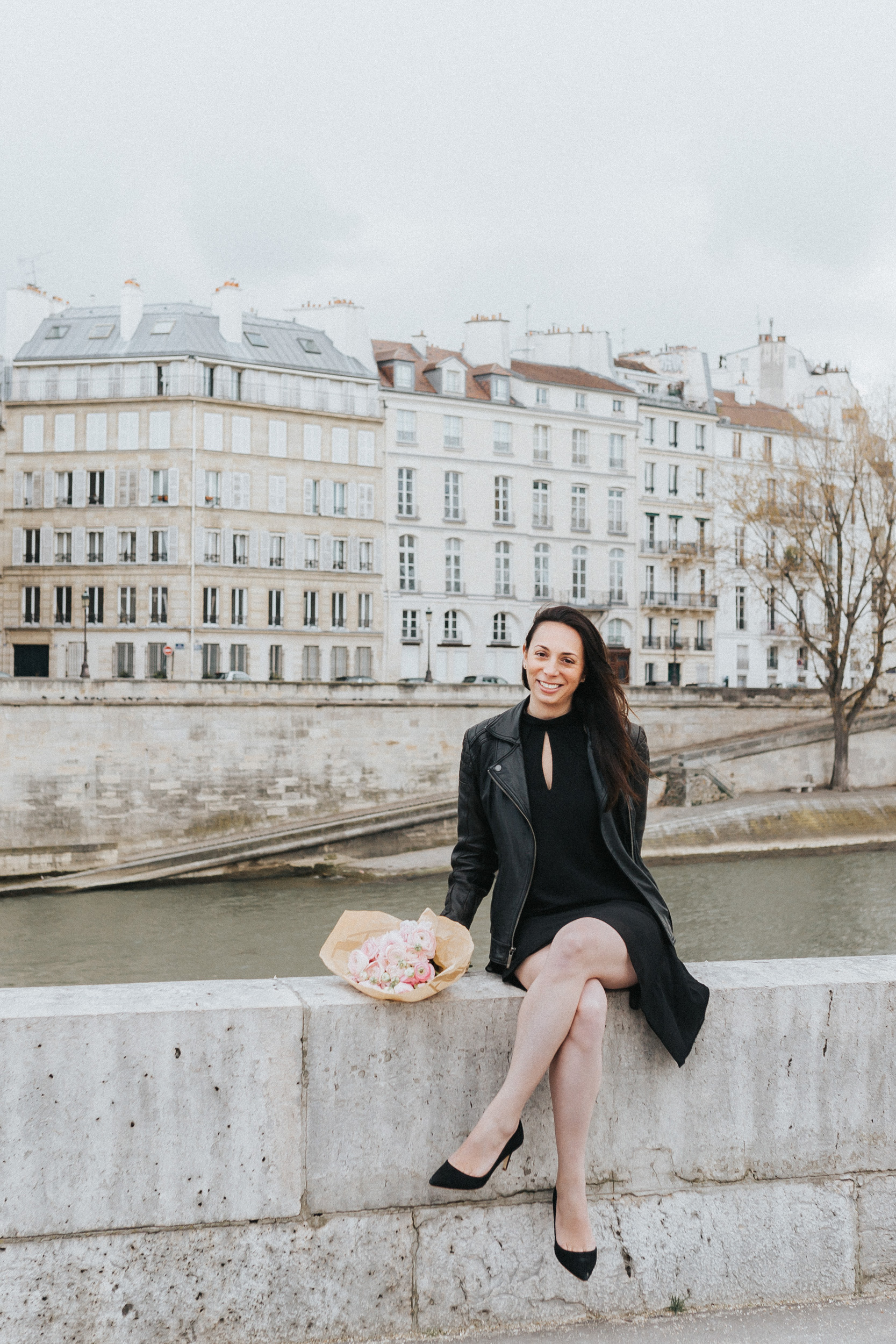 Spring portrait of Rebecca Plotnick founder of Every Day Parisian blog sitting by the Seine river and Ile Saint Louis with bouquet of ranunculus captured by Paris Photographer Federico and Anastasia Guendel IheartParisFr TheFlyingPoodle
