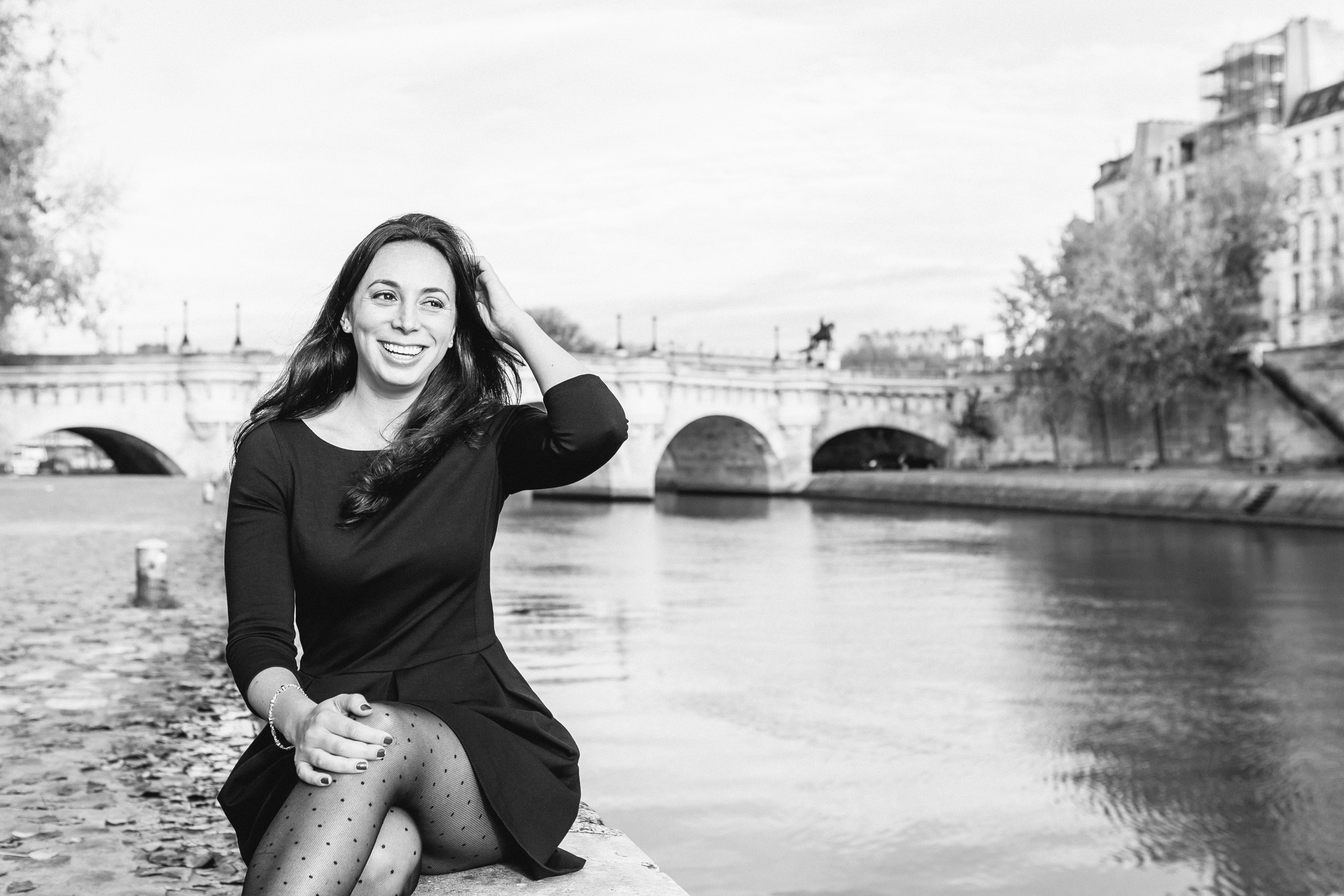 Black and white portrait of Rebecca Plotnick founder of Every Day Parisian blog sitting by the Seine river captured by Paris Photographer Federico and Anastasia Guendel IheartParisFr TheFlyingPoodle