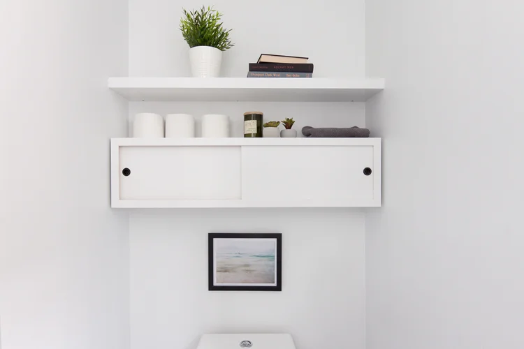 In the tiny powder room, custom cabinetry for storage