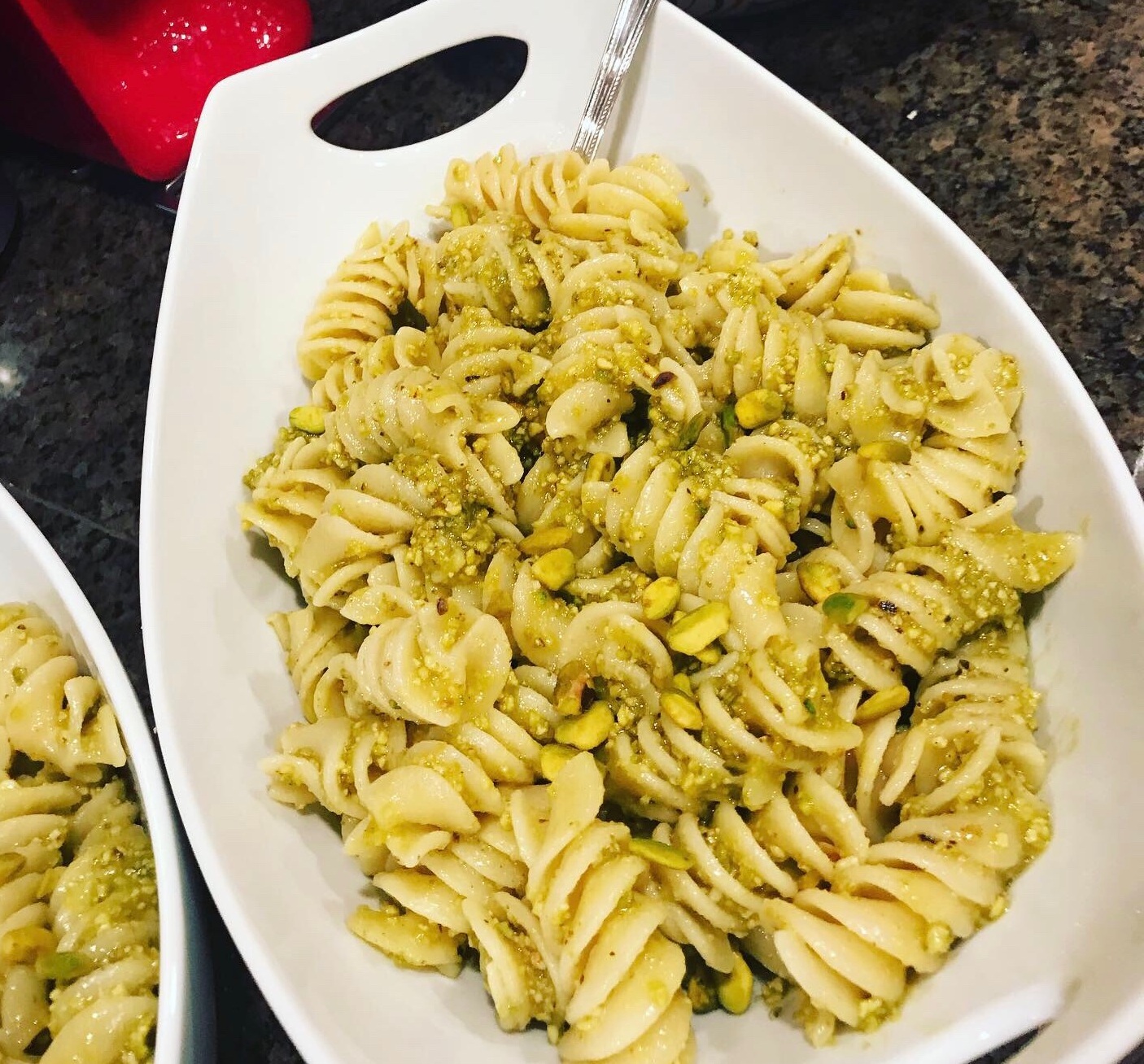 Pistachio pesto tossed with spiral pasta in a white dish