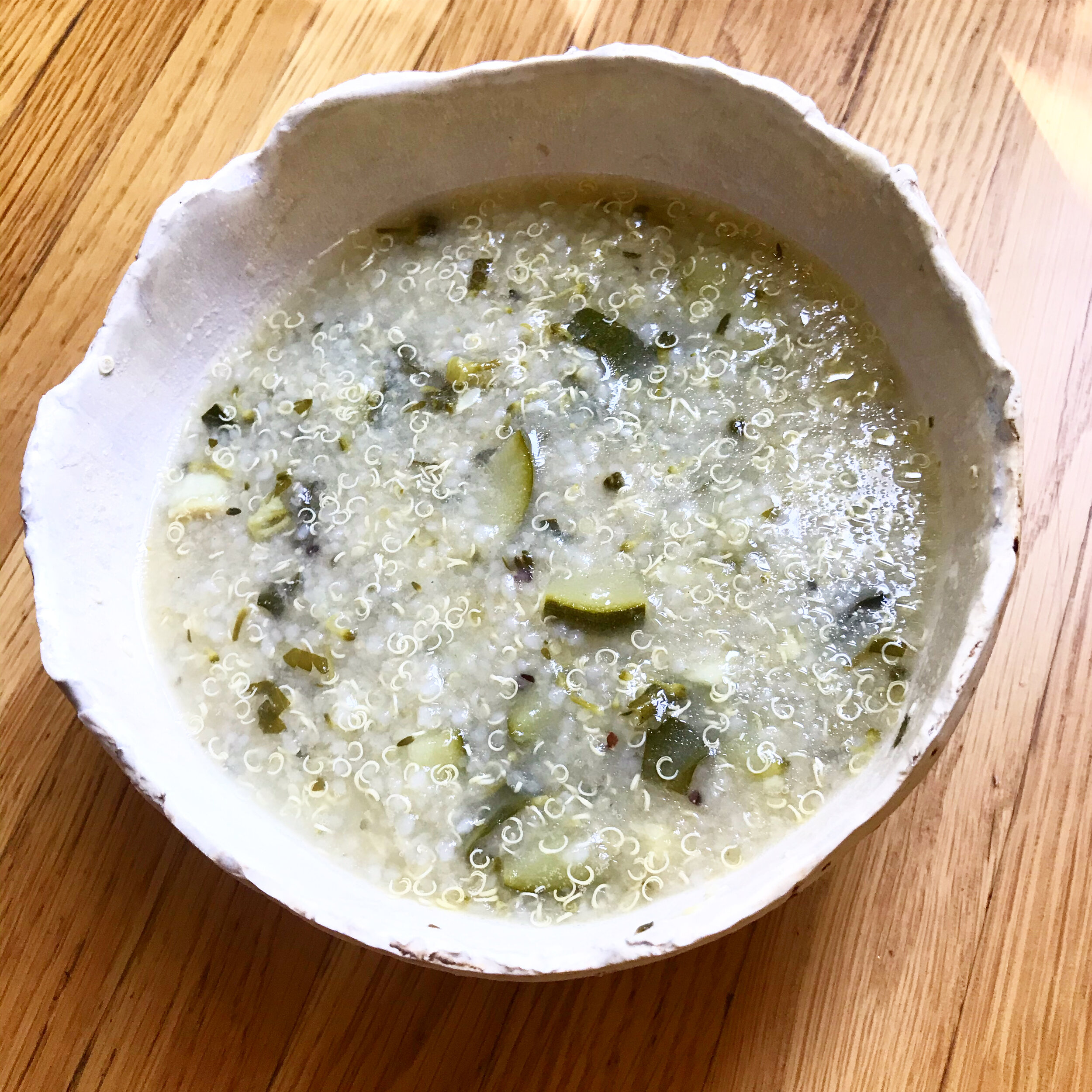 Savory quinoa and vegetable porridge in a white bowl