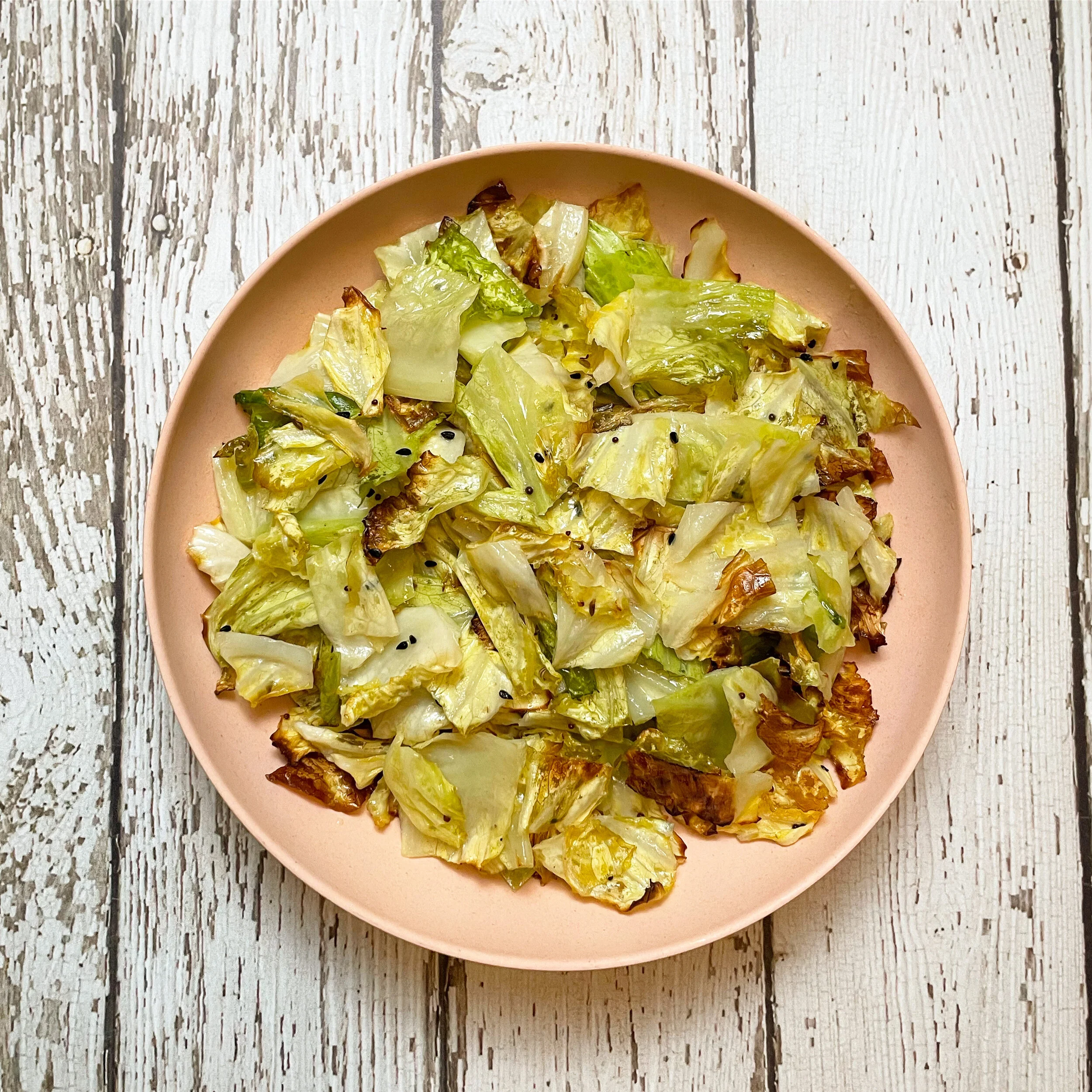 Roasted savoy cabbage seasoned with spices and herbs and presented in a pale coral dish