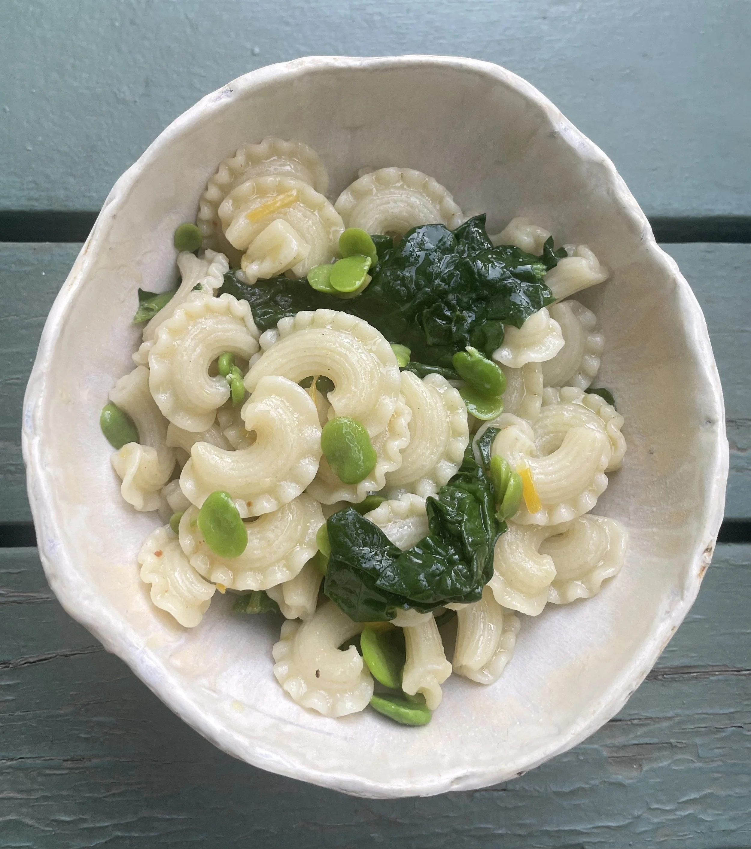 Pasta with fava beans, spinach, and Meyer lemon in a white bowl