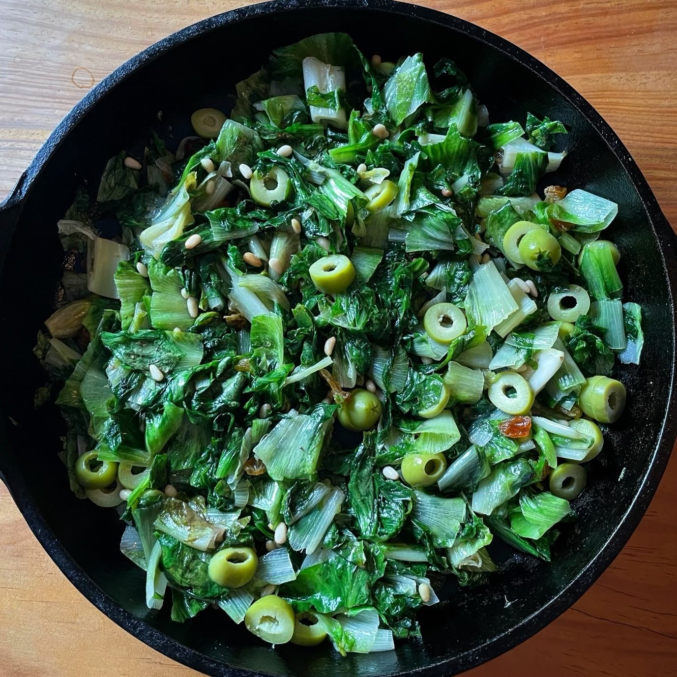 Scarola alla Napoletana with escarole, olives, and capers in a skillet