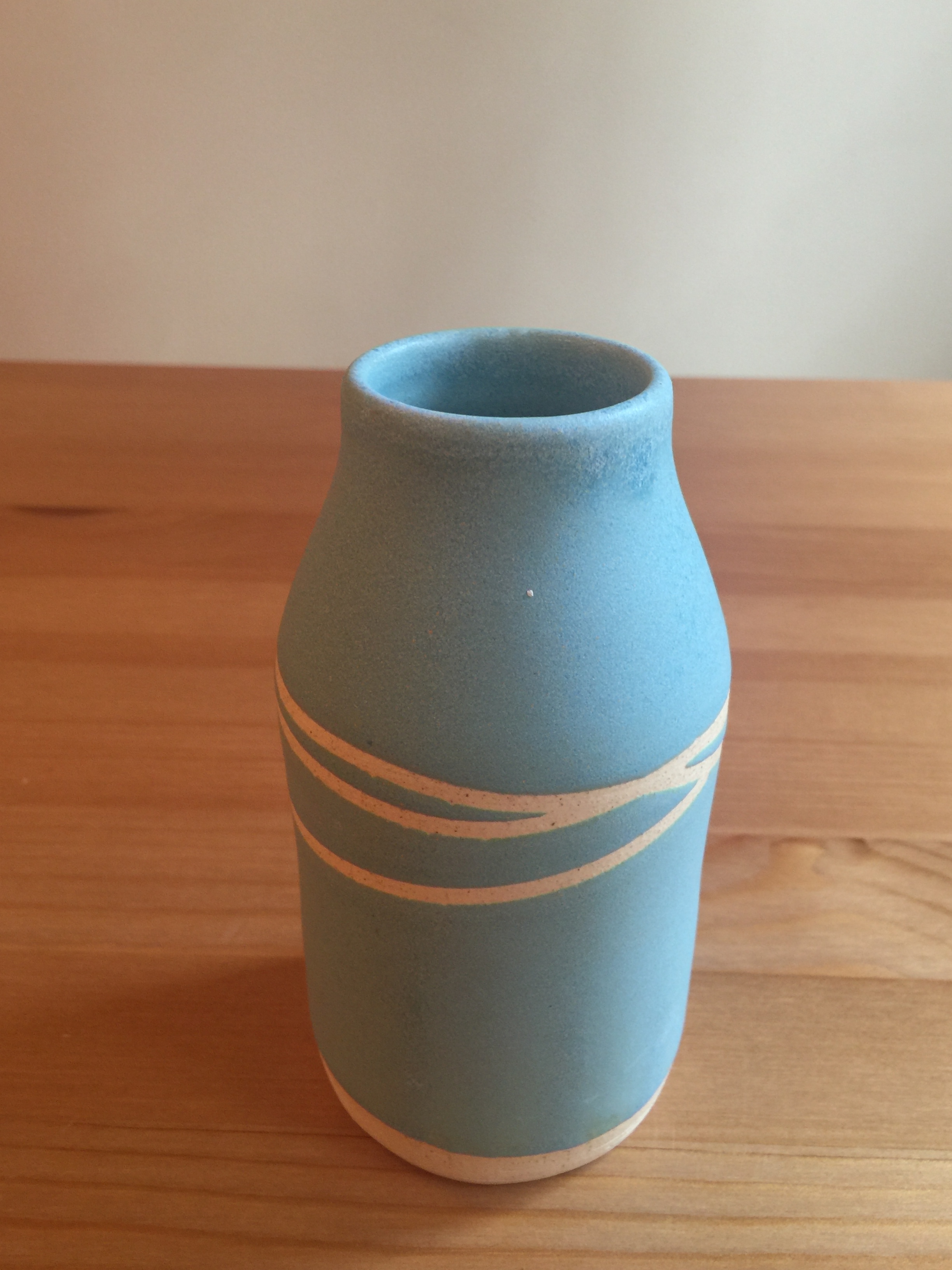 small vase: teal glaze with raw clay resist design