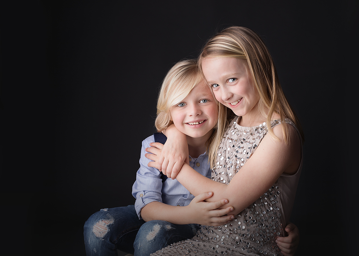 beautiful smiling siblings photographed studio session black background at candace hires photography st simons island ga