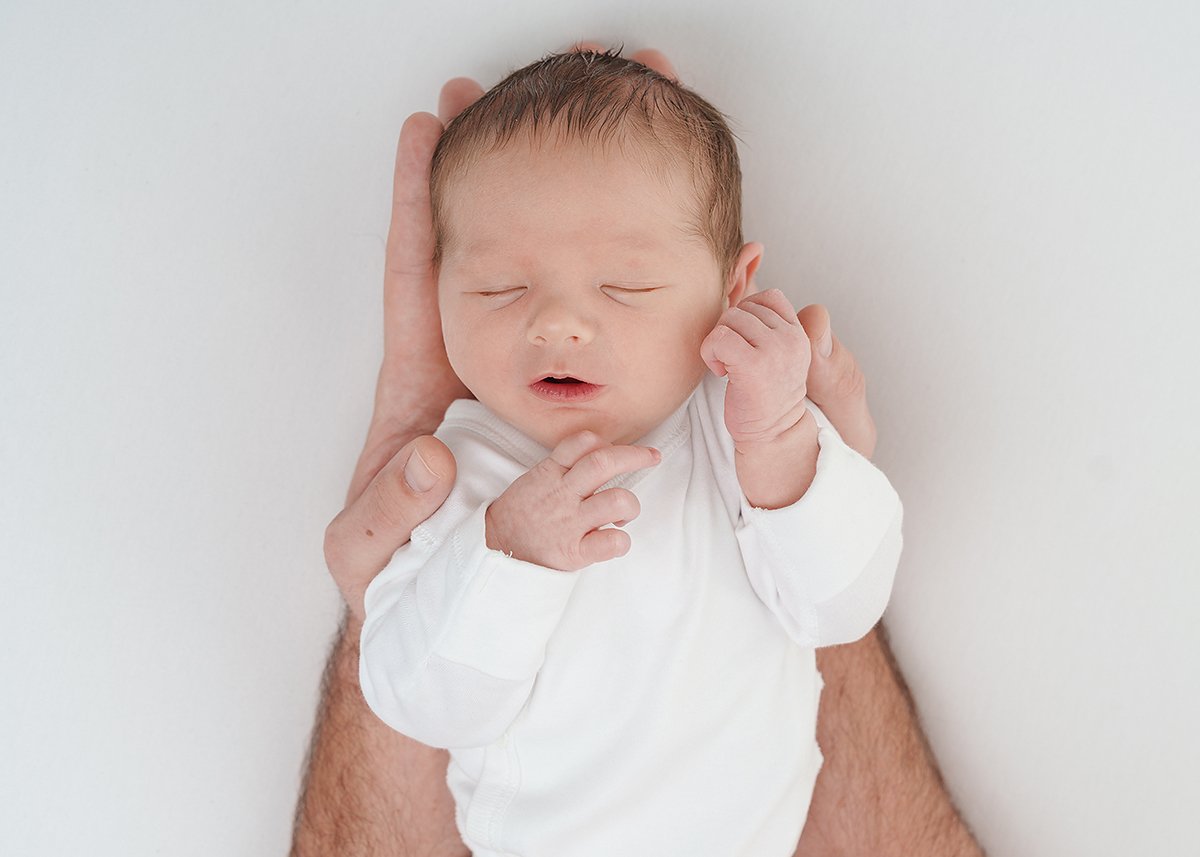newborn baby photographed being held in dads hands
