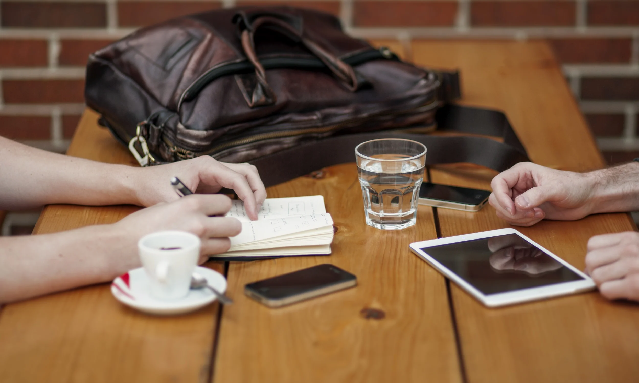 people_taking_notes_with_devices_on_a_table.jpg