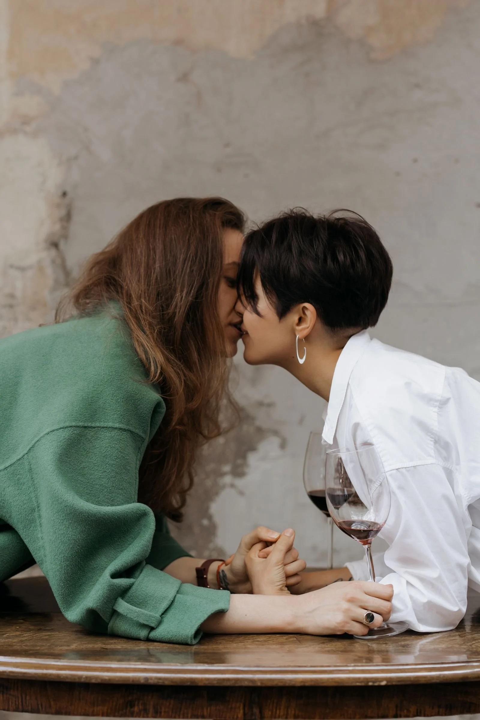Honeymoon couple sharing a kiss over red wine in Italy