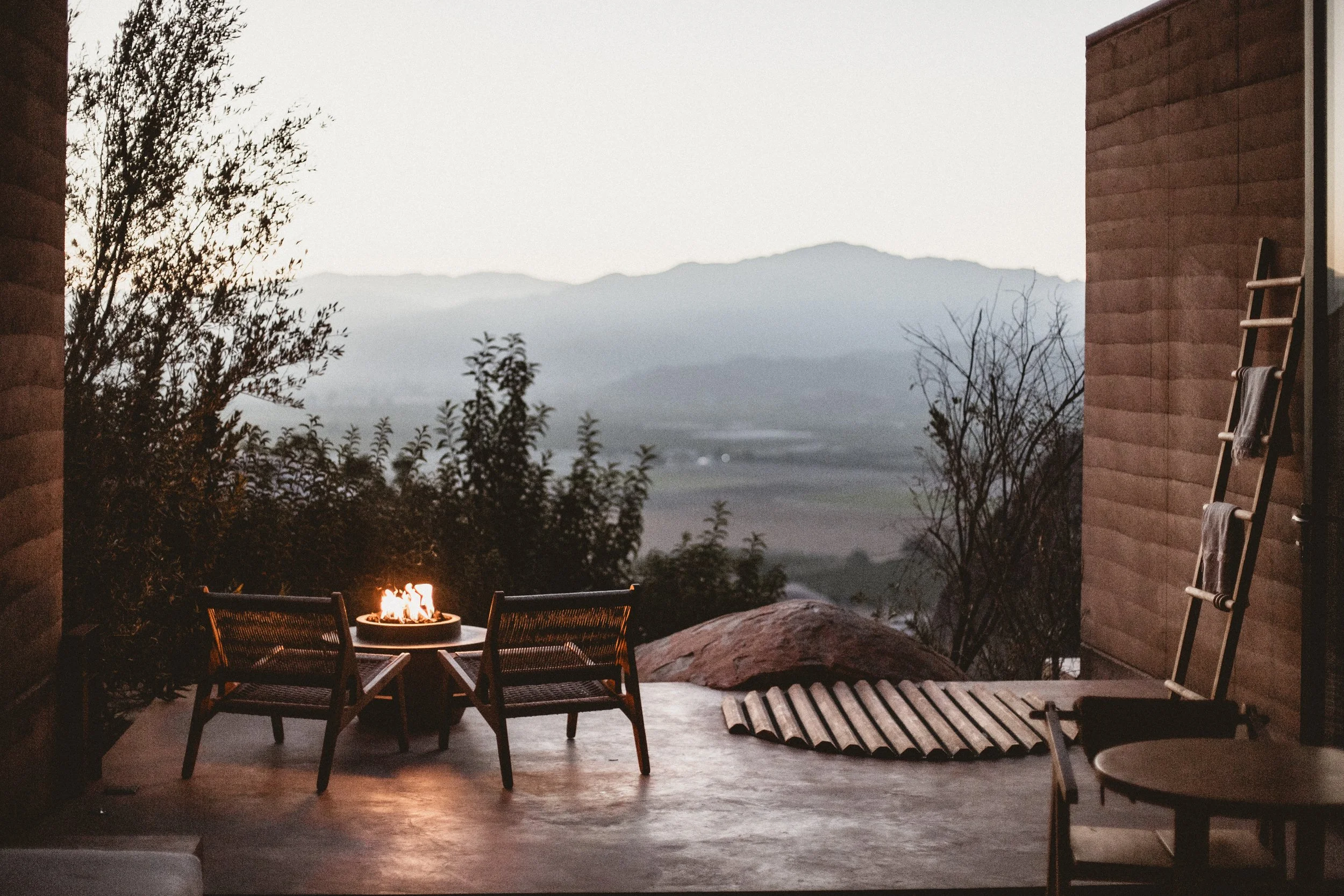Mira Earth Studio balcony with chairs and fire pit hazy view of Valle de Guadalupe valley