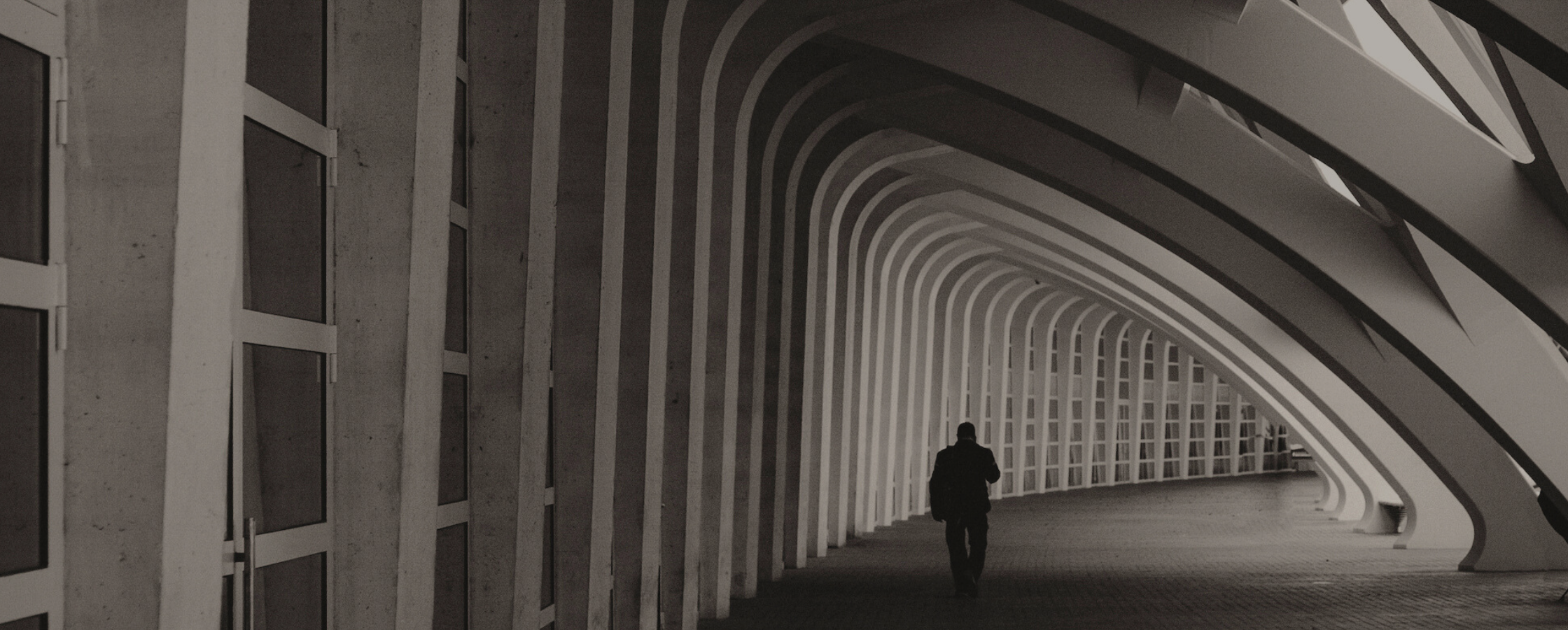 Man walking alone though an architectural tunnel