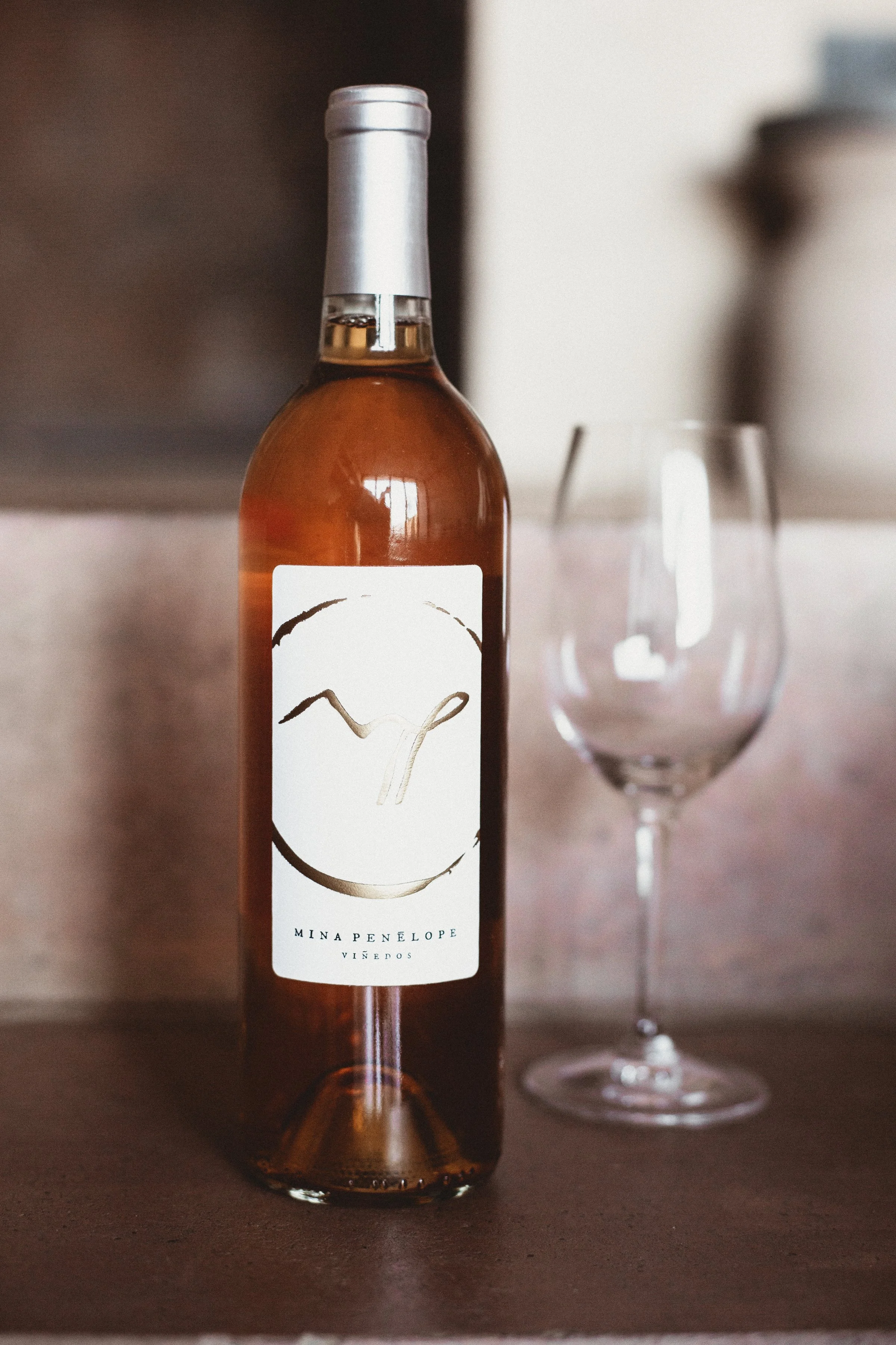 Bottle of rose from Mina Penelope next to empty wine glass