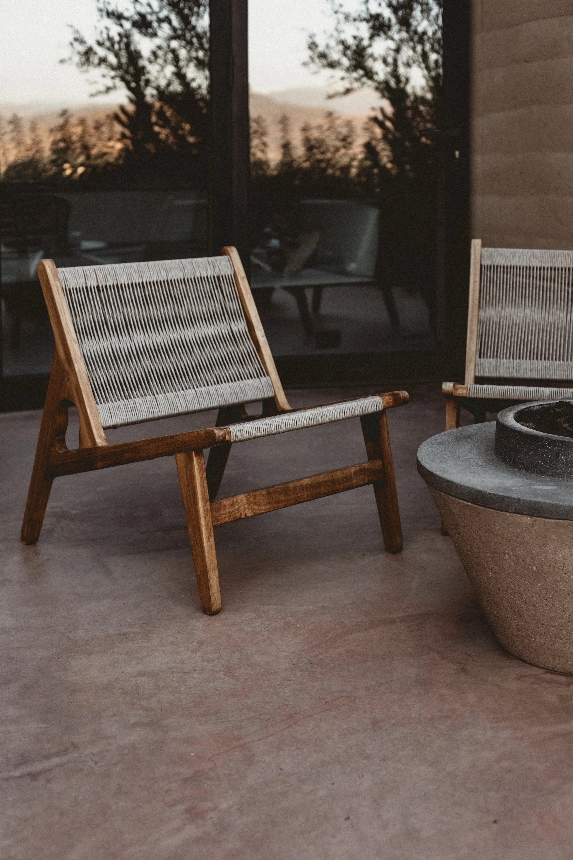 Two wood framed chairs with woven seats near fire pit