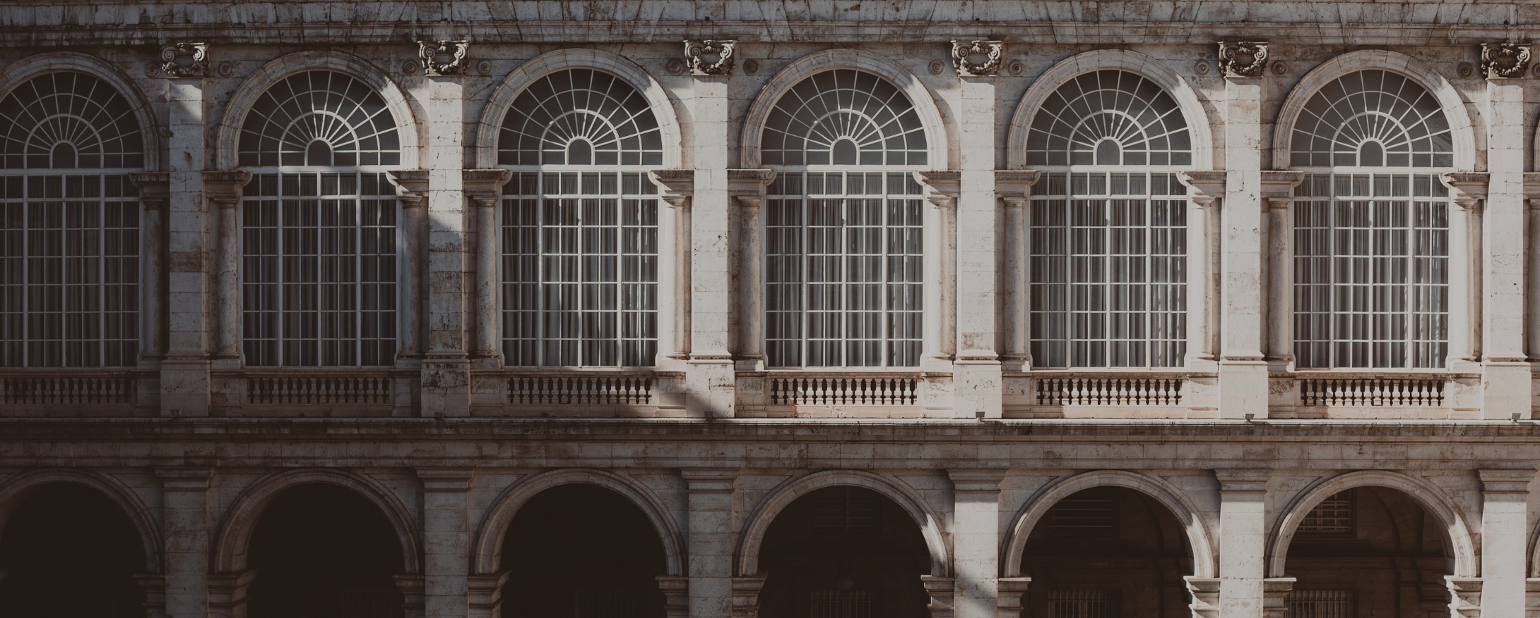 Slant light over arched windows in courtyard of royal palace in Madrid