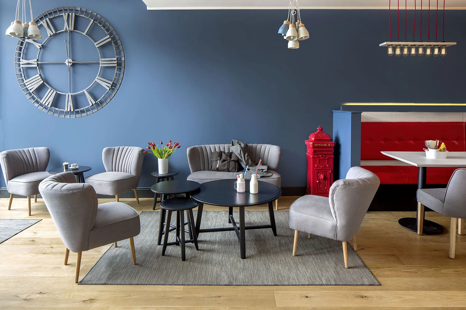 The coffee/ Milkshake area adds a clever social aspect to this diner. Where clients can order a soft drink in the morning and work on their laptop, or have cocktail milkshake in the evening and chat to friends, perfect for those who are not there for a meal.&nbsp;The muted Grey chairs and dark blue walls allow the bold reds, that of a typical diner, to stand out. The cluster of pendant lamps mixed in with the 3 nest of tables add to the mix of elevating the diner to a contemporary aesthetic. 