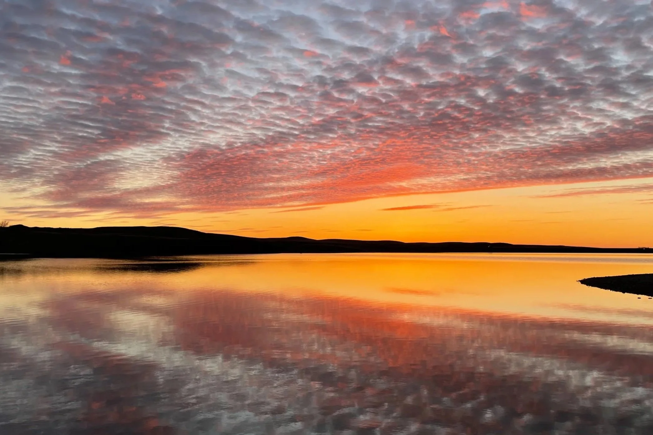 Sunset over a body of water with clouds in the sky.