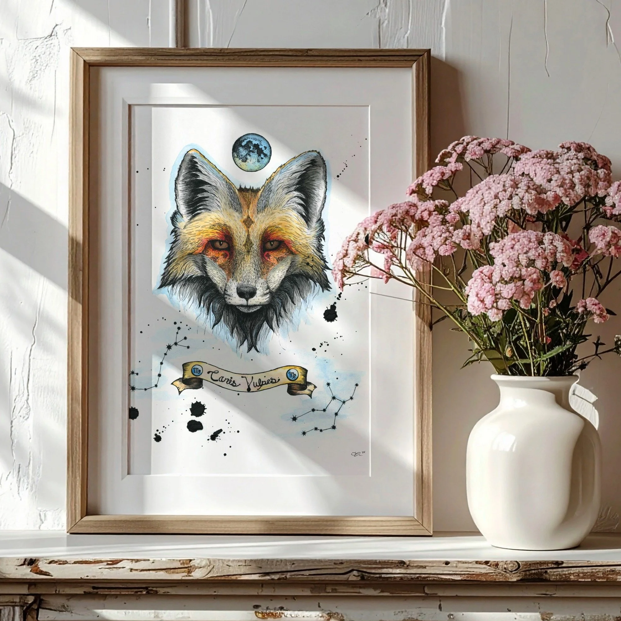Framed artwork of a fox with a moon above its head, decorative elements, and a banner with the text 'Canis Vulpis' next to a vase of pink flowers.