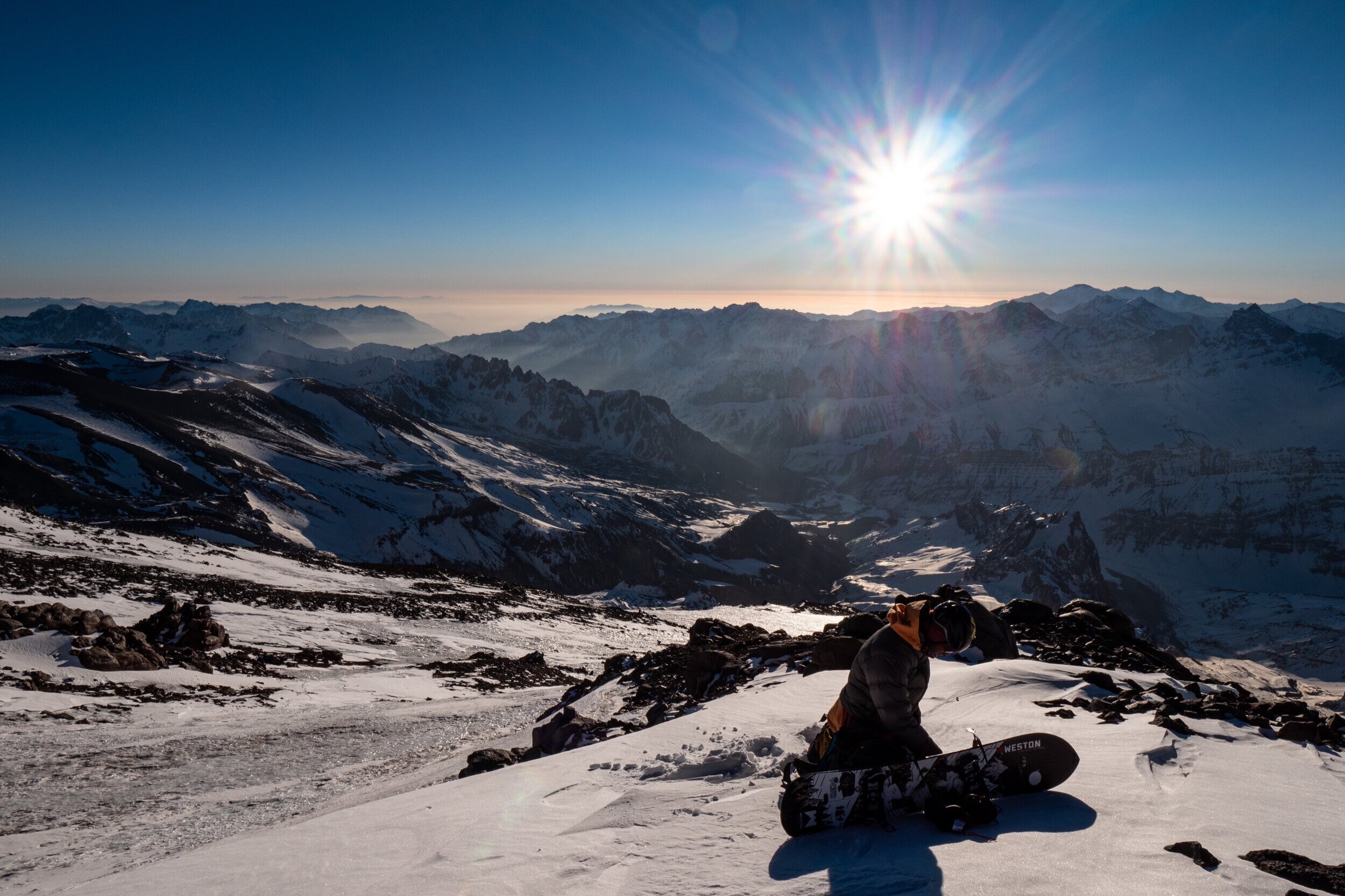 Rafael Pease taking a break from his snowboard descent at around 5,800meters (19,000ft) before continuing to snowboard down the blue and white ice.