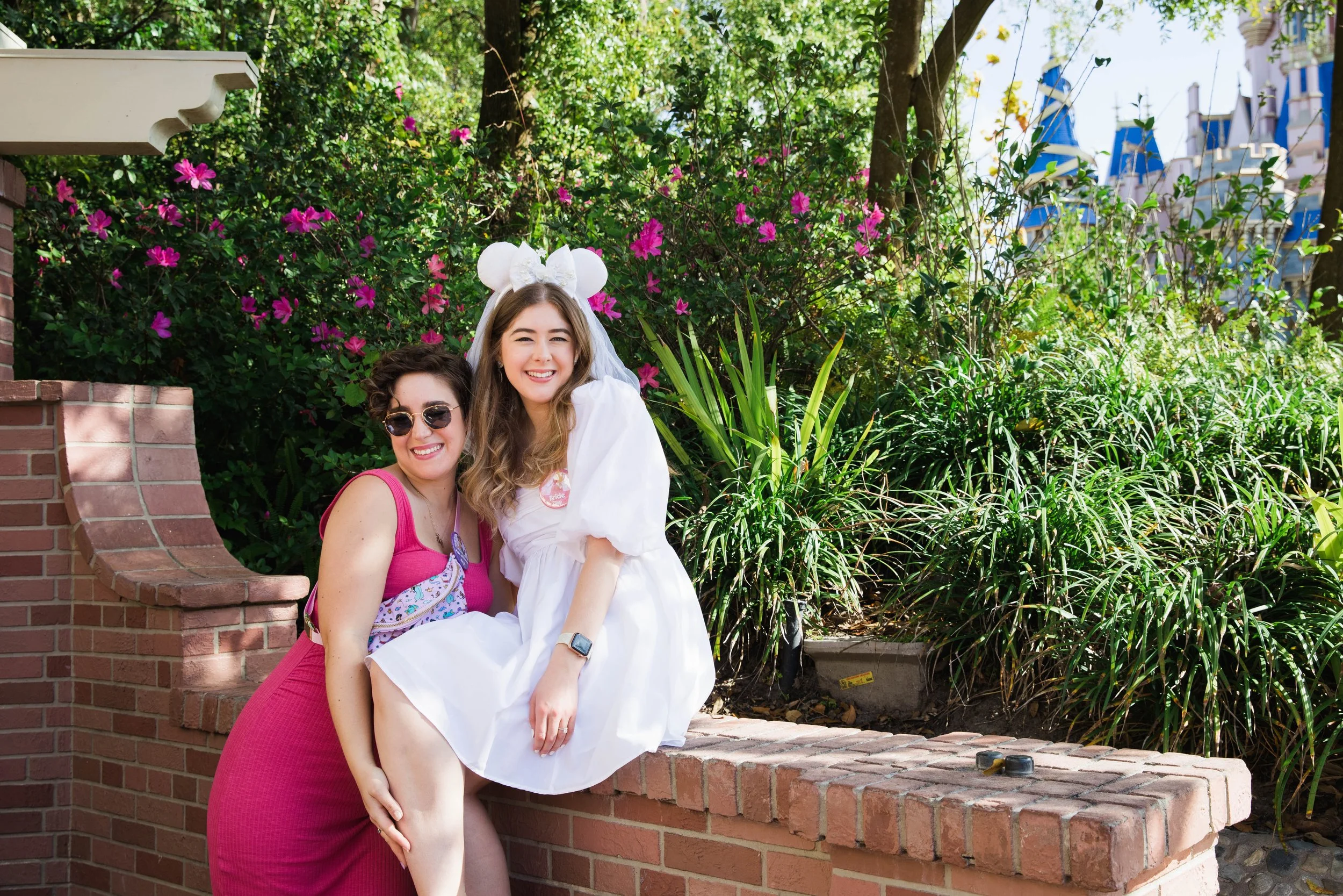 Bride to be and maid of honor pose in front of Cinderella Castle.