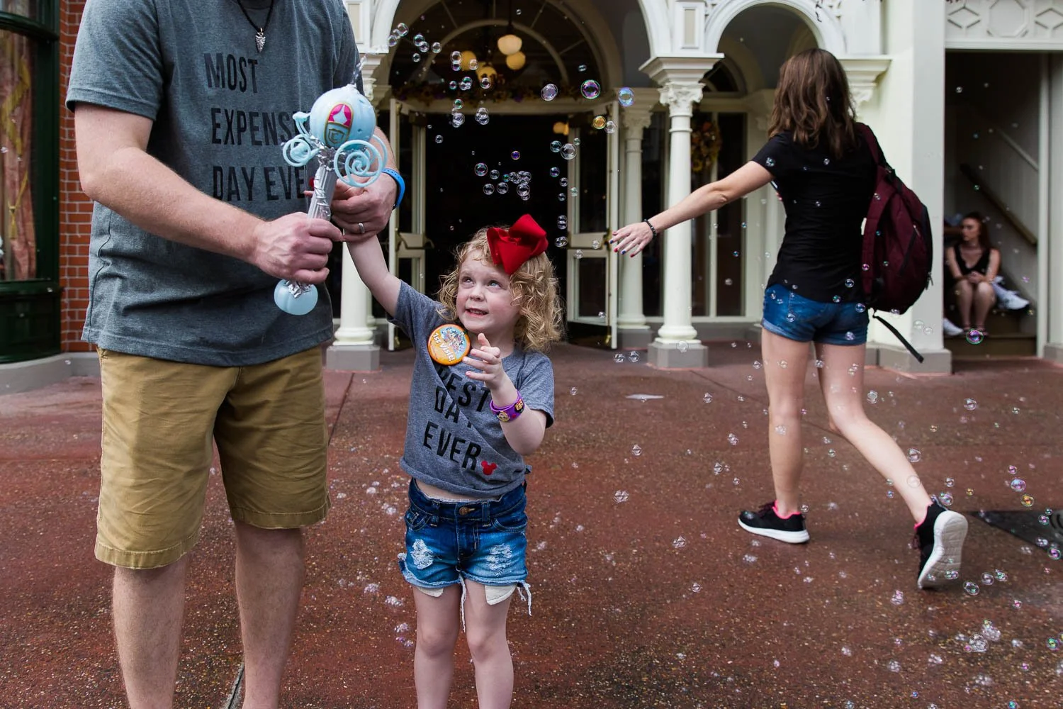 Father and daughter play with bubble wand on Main Street USA.