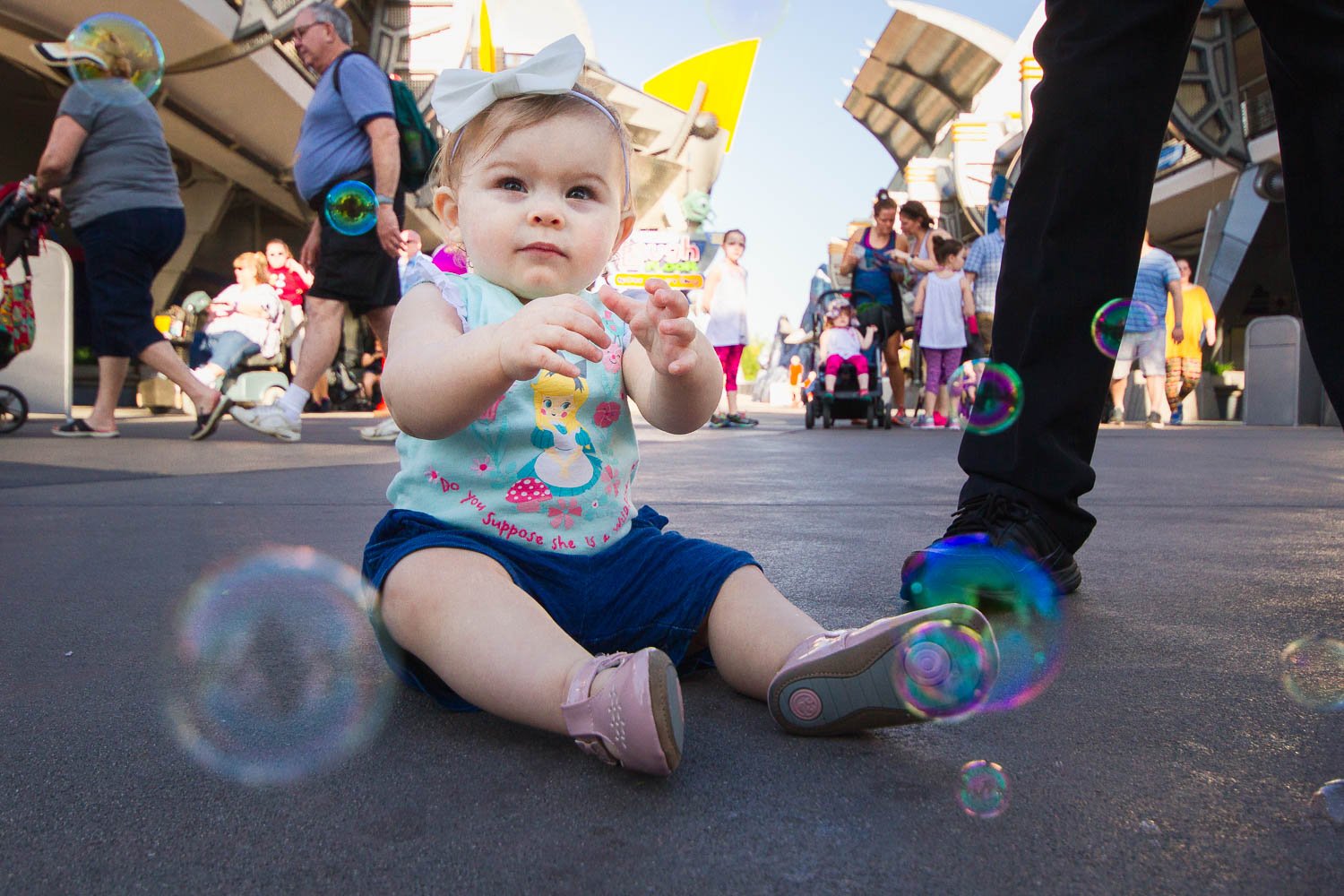 Cast member blows bubbles for a baby in Tomorrowland.