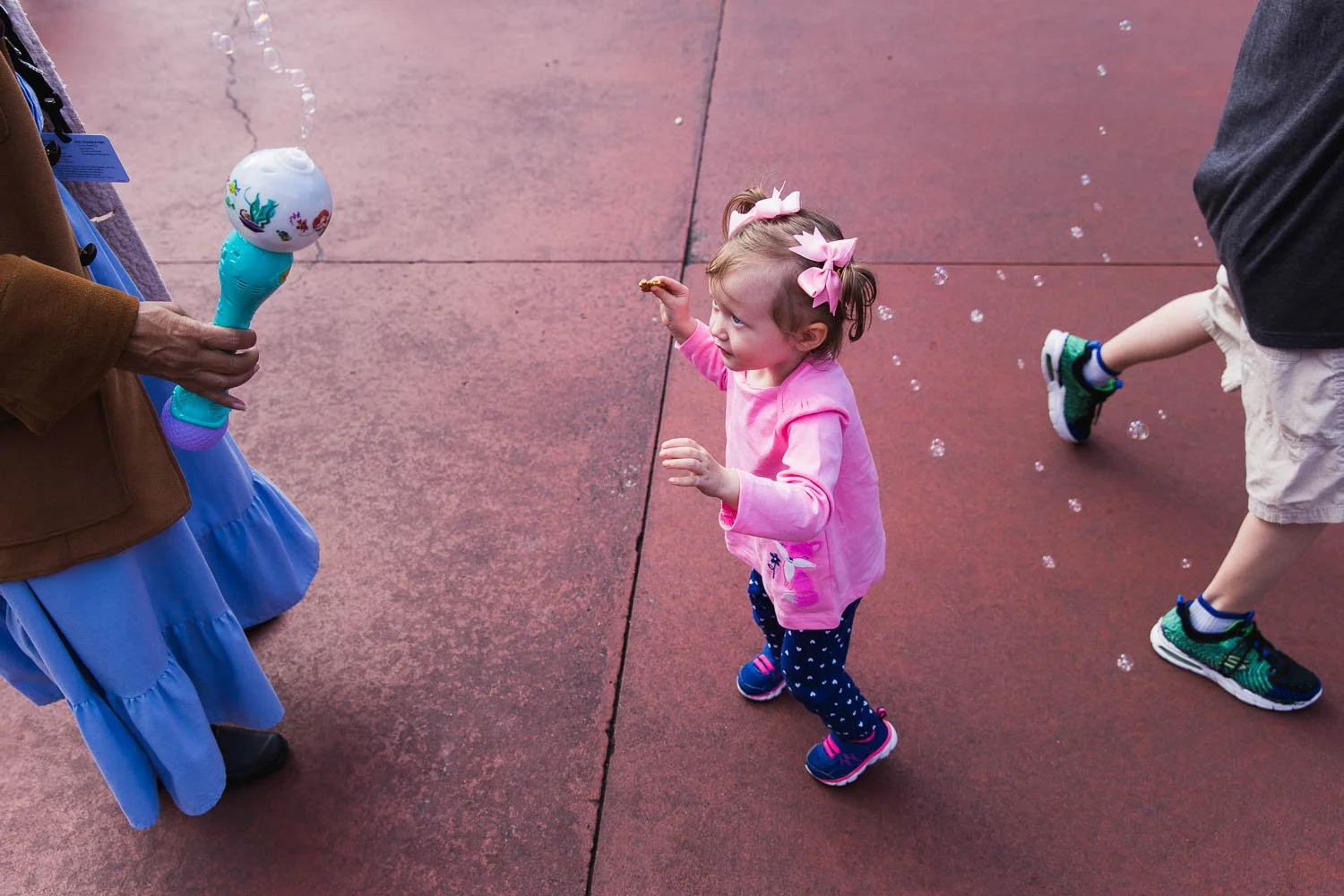 Cast Member blows bubbles for a toddler at the Magic Kingdom.