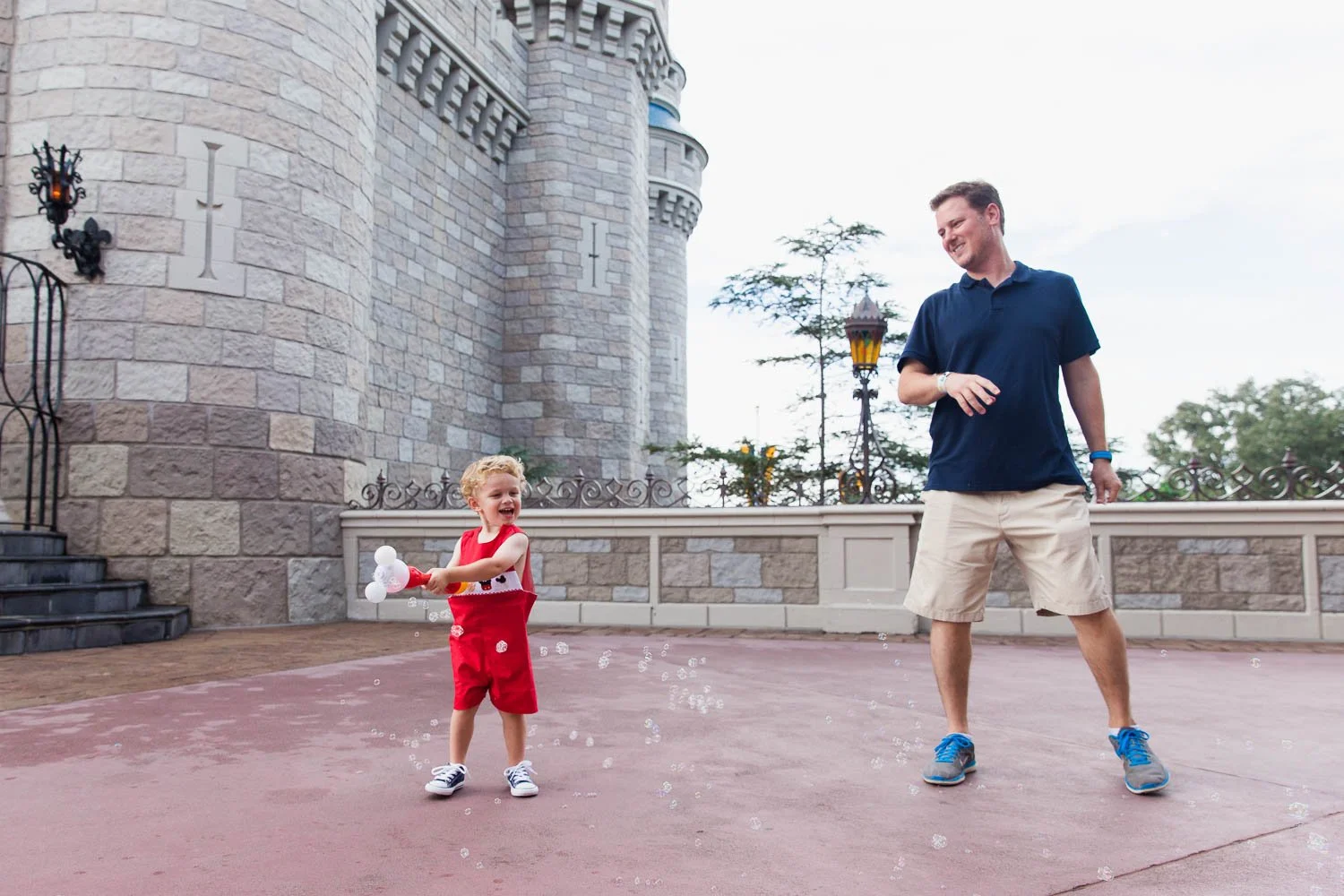 Father and son play with bubbles behind Cinderella Castle at the Magic Kingdom.